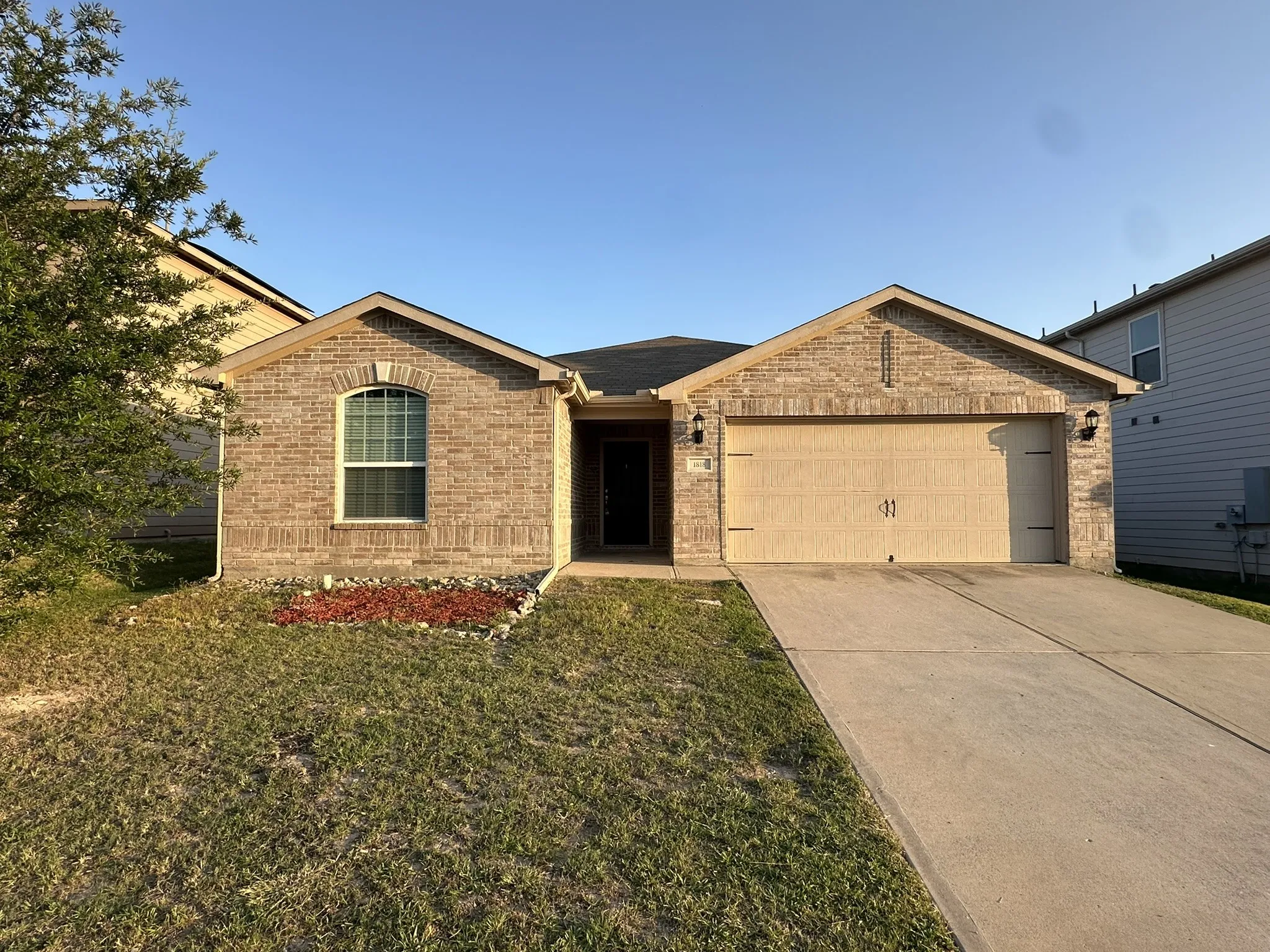 Brick facade residence featuring an arched window, a two-car garage with decorative hardware, and a concrete driveway