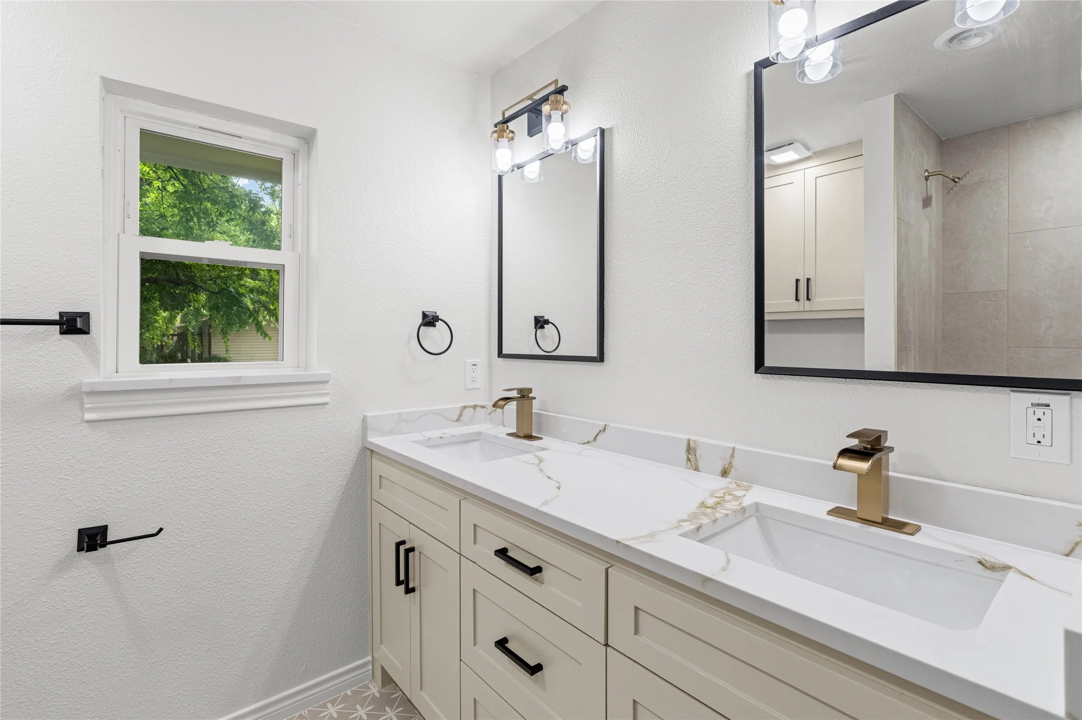 Dual vanity featuring undermount sinks, gold-tone faucets, and marble-look countertops