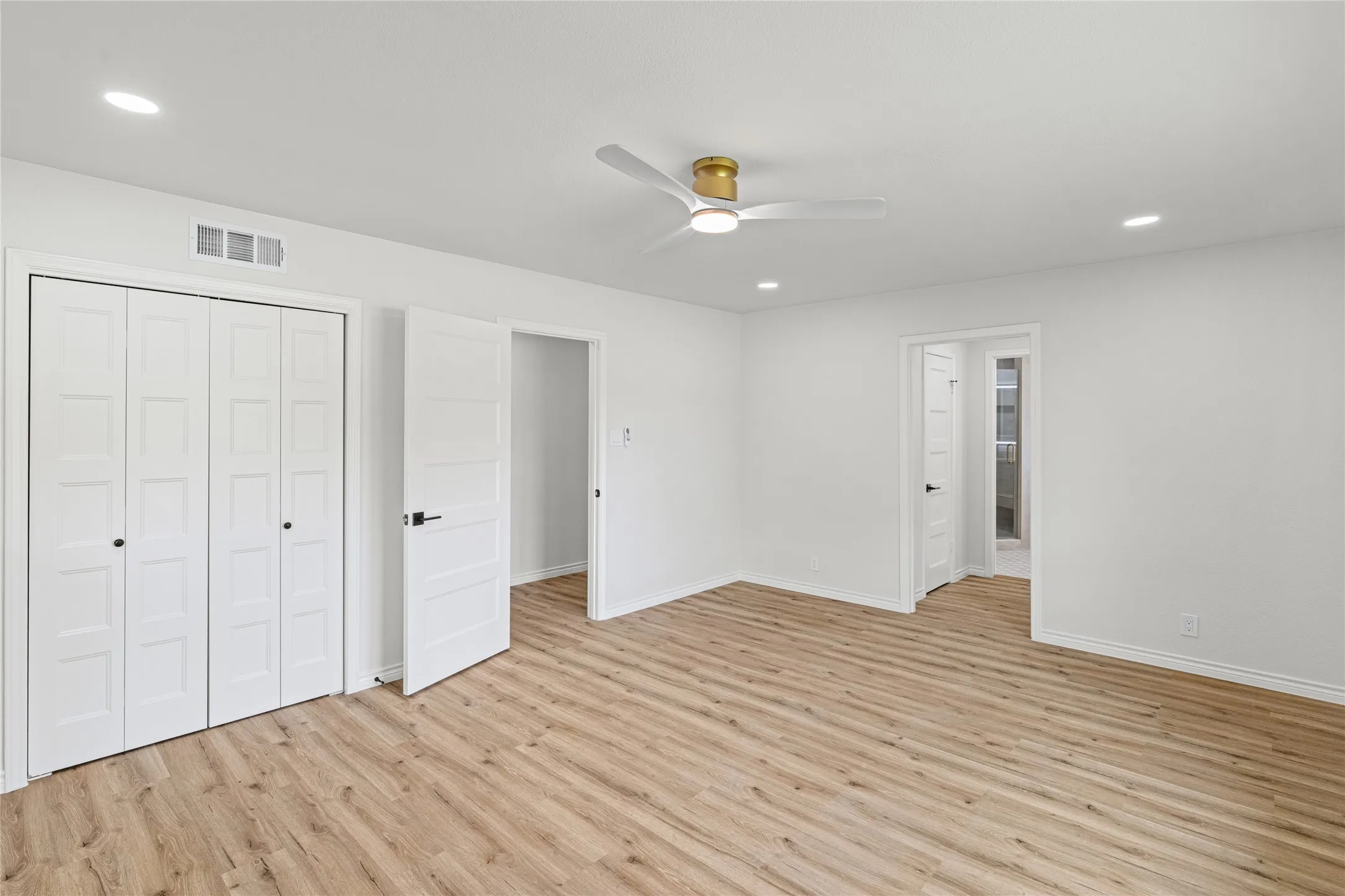 Spacious room featuring wood-finish flooring and bright white walls
