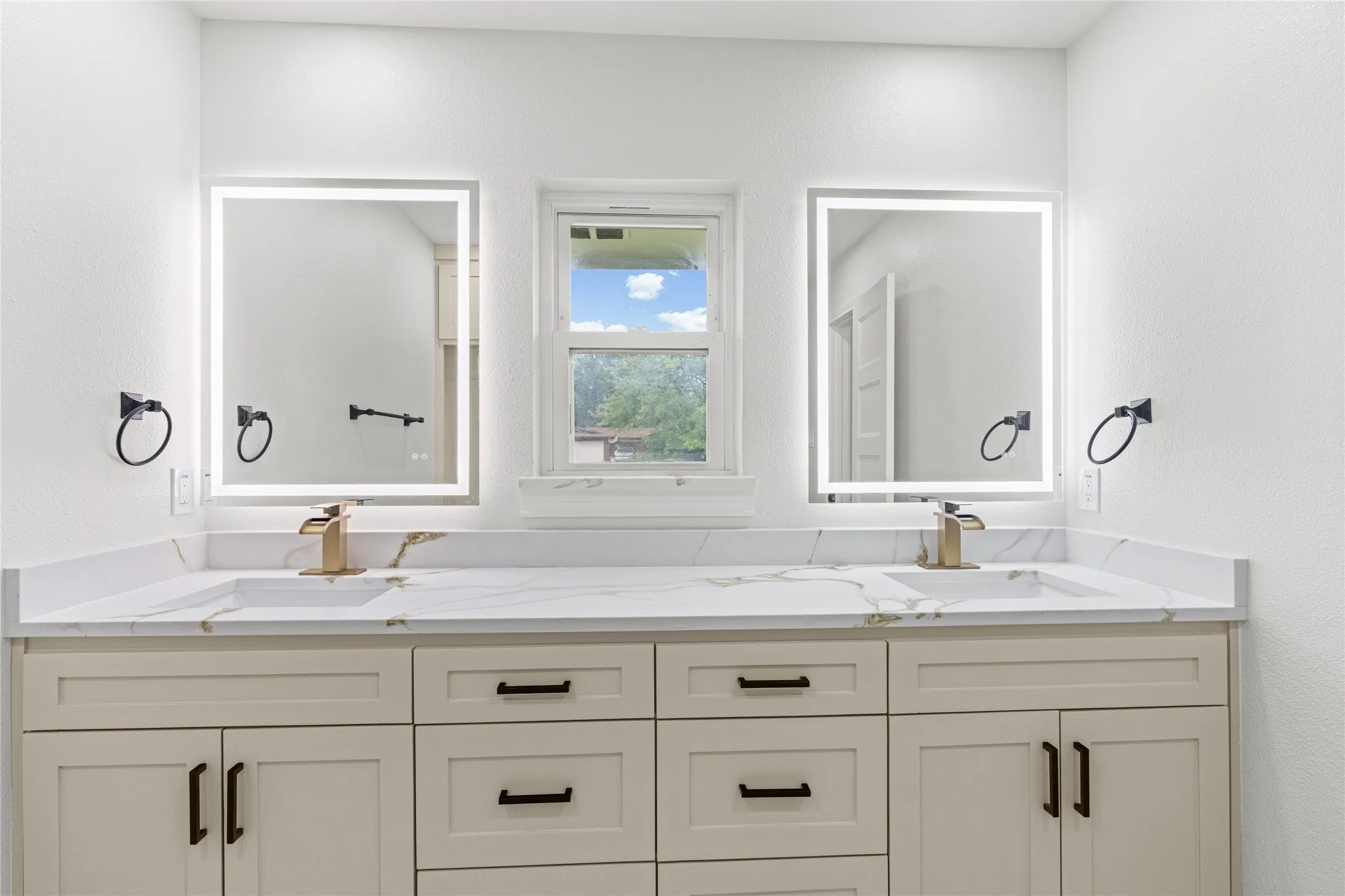 Dual vanity with integrated sinks, white marble-patterned countertops, and light-toned cabinetry