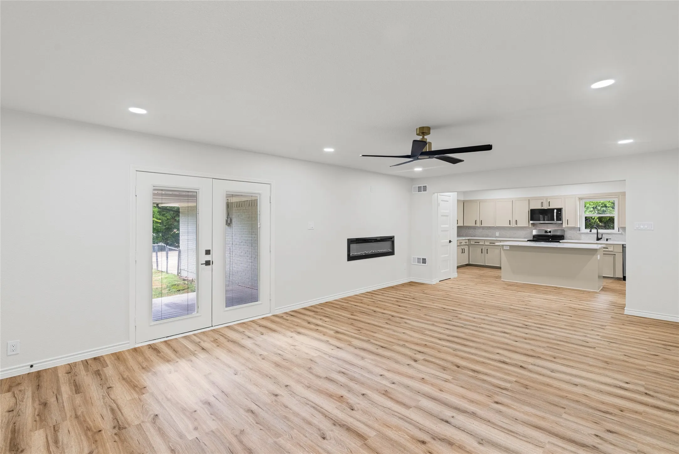 Open-concept living space featuring wood-finish flooring, recessed lighting, and a modern ceiling fan