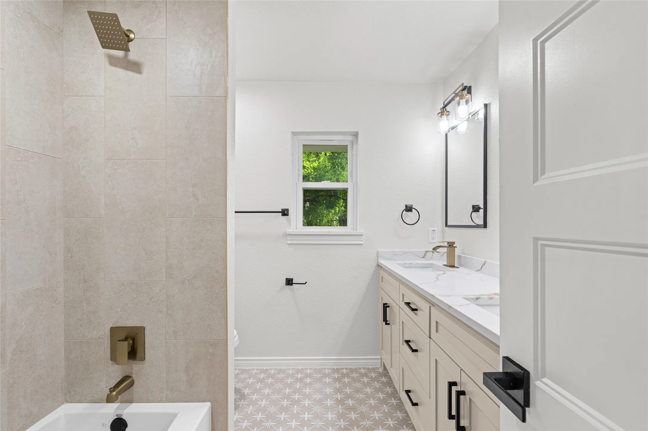 Bathroom featuring a dual vanity with light-toned cabinetry, a stone-finish countertop, and undermount sinks