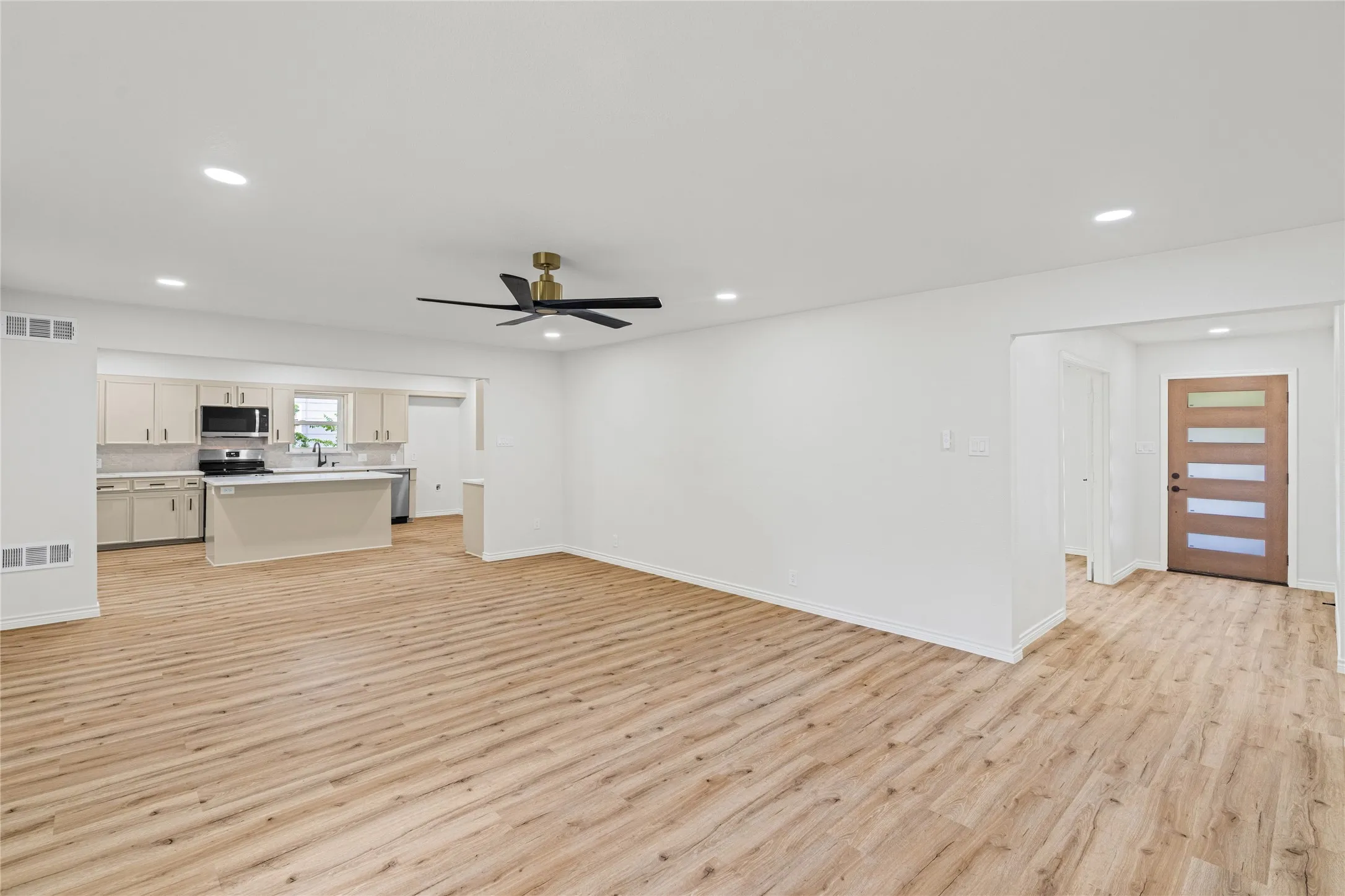 Open-concept living area featuring wood-finish flooring, recessed lighting, and a modern ceiling fan