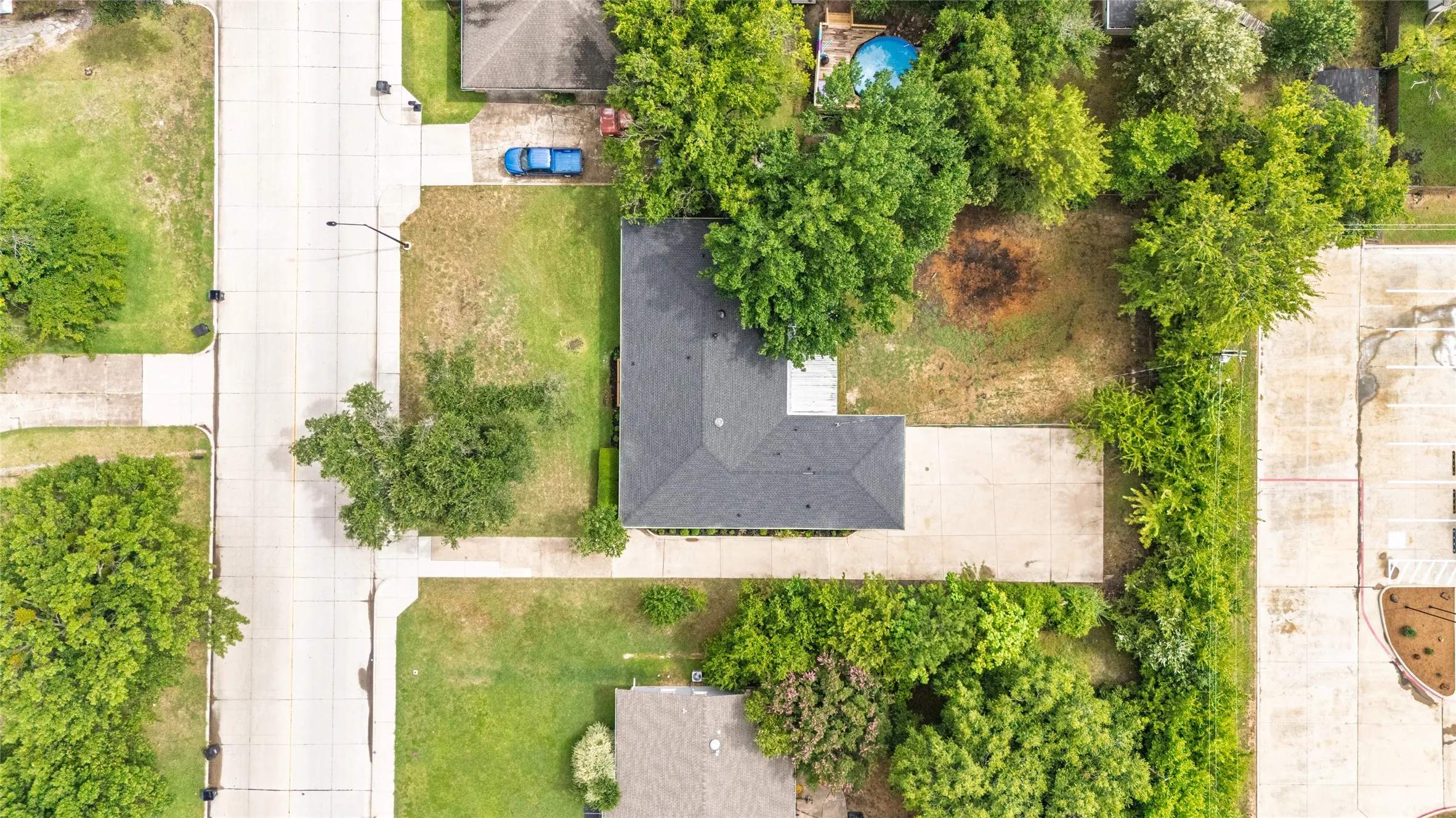 Property features a dark shingle roof and extensive concrete driveway