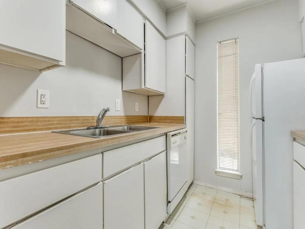 Kitchen featuring white cabinetry, a double basin stainless steel sink, wood-finish countertops, and a full-size refrigerator