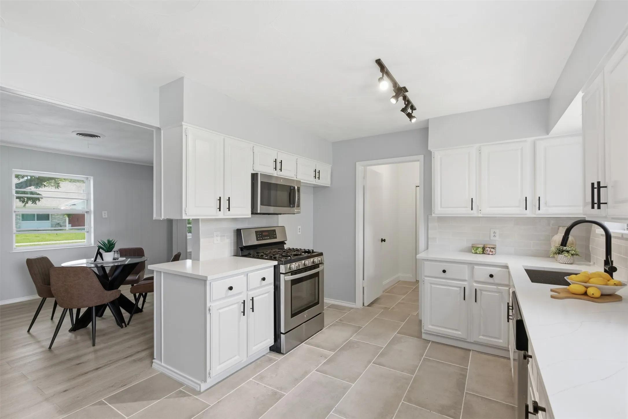 Remodeled Kitchen with Room to Work — Generous countertops, abundant white cabinetry, tile flooring, updated fixtures, and a large window create a bright, functional kitchen designed for effortless meal preparation.