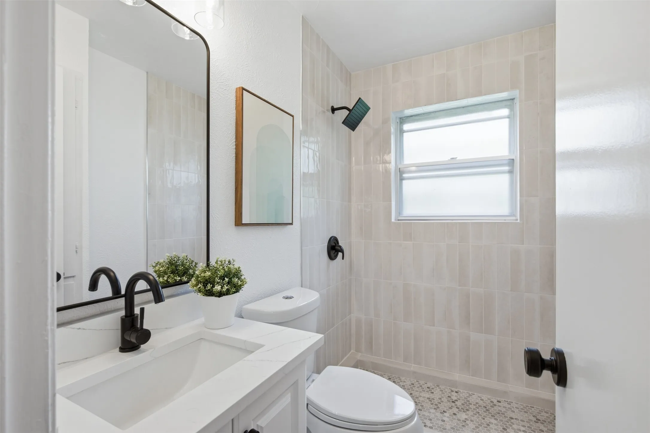 Refreshingly Updated Primary Bath — Full-height shower tile, a walk-in shower, a modern vanity, and matte black fixtures give the primary bath a clean, contemporary finish.