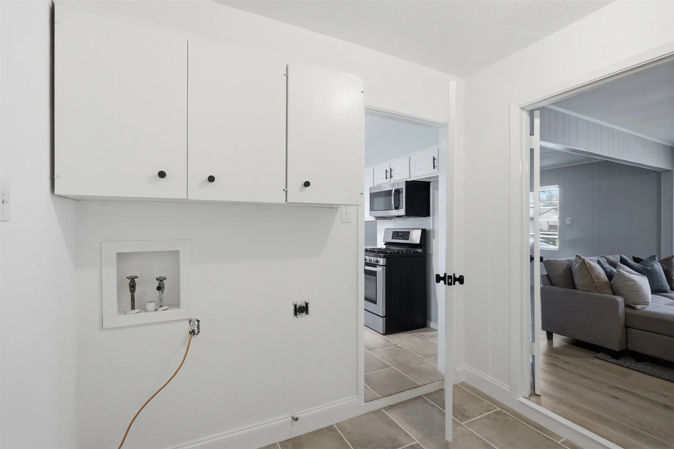 Convenient Dedicated Laundry Space — Located just off the kitchen and living area, the tiled laundry room includes washer and dryer connections plus overhead cabinetry for organized household storage.