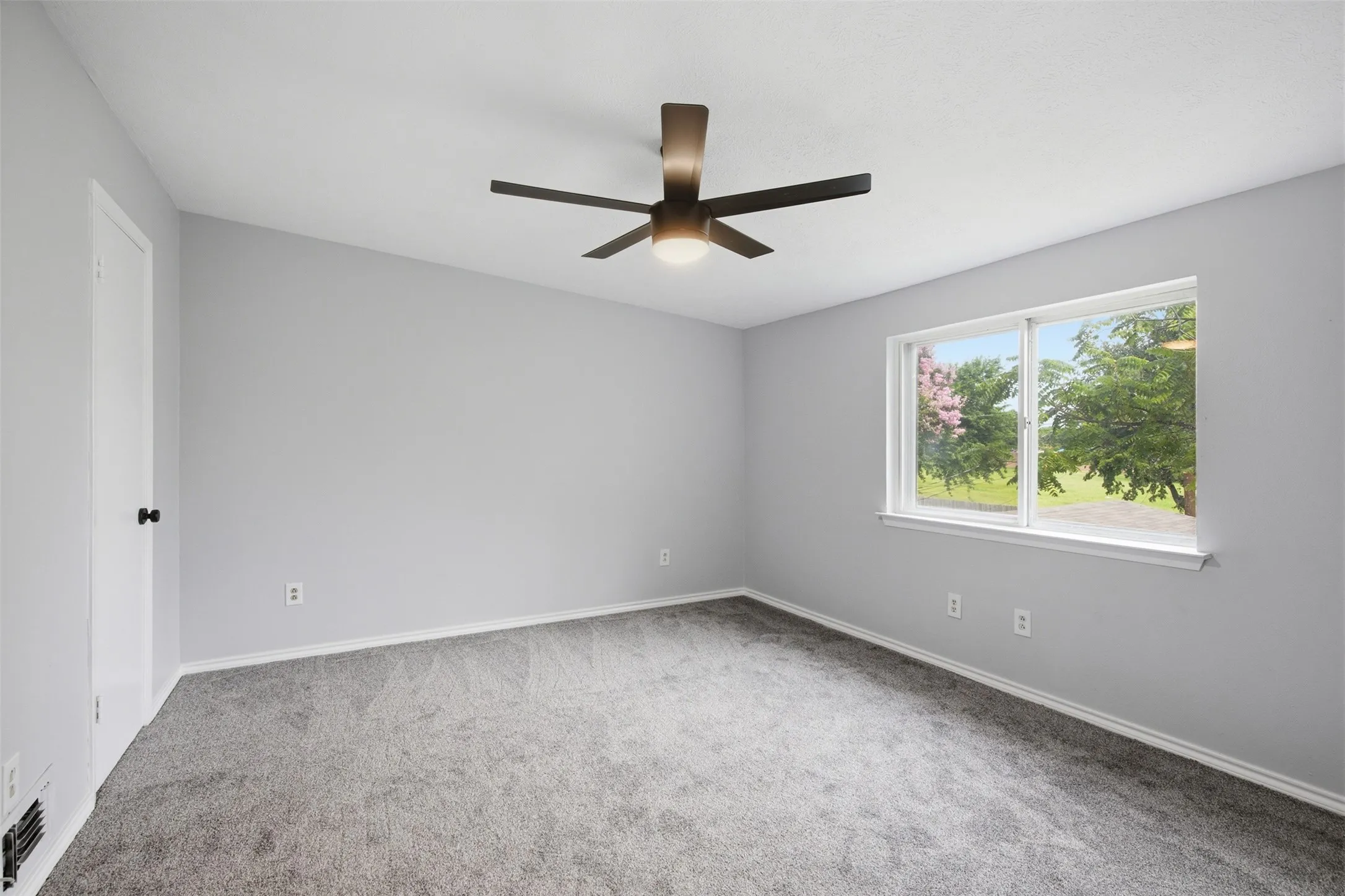 Spacious Fourth Bedroom — Fresh paint, new carpet, a modern ceiling fan, and a broad window create a bright upstairs bedroom with plenty of room for a comfortable furniture arrangement.