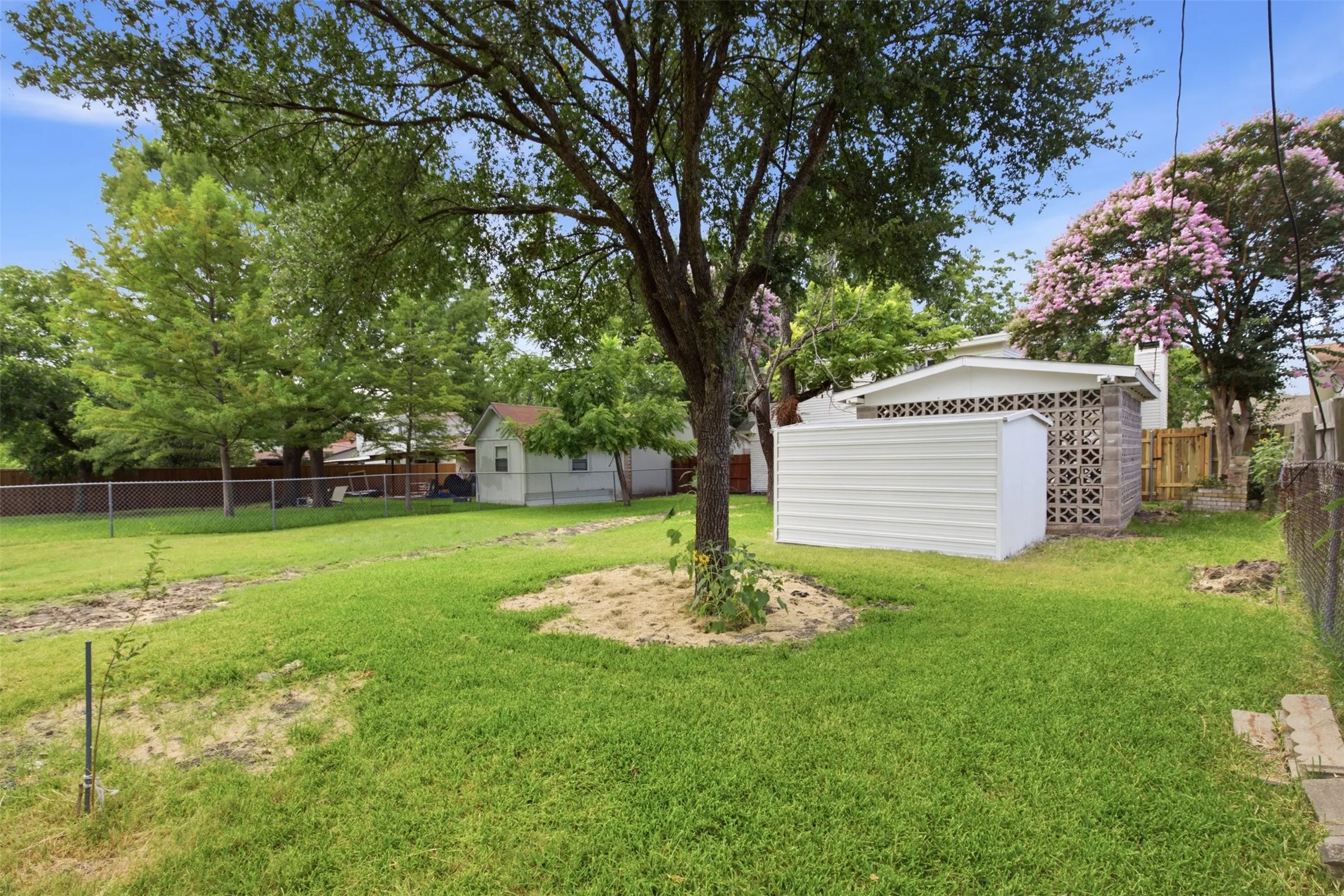 Outdoor Space with Added Storage — A storage shed and covered structure provide useful space for tools, lawn equipment, or hobby gear while preserving plenty of room to enjoy the yard.
