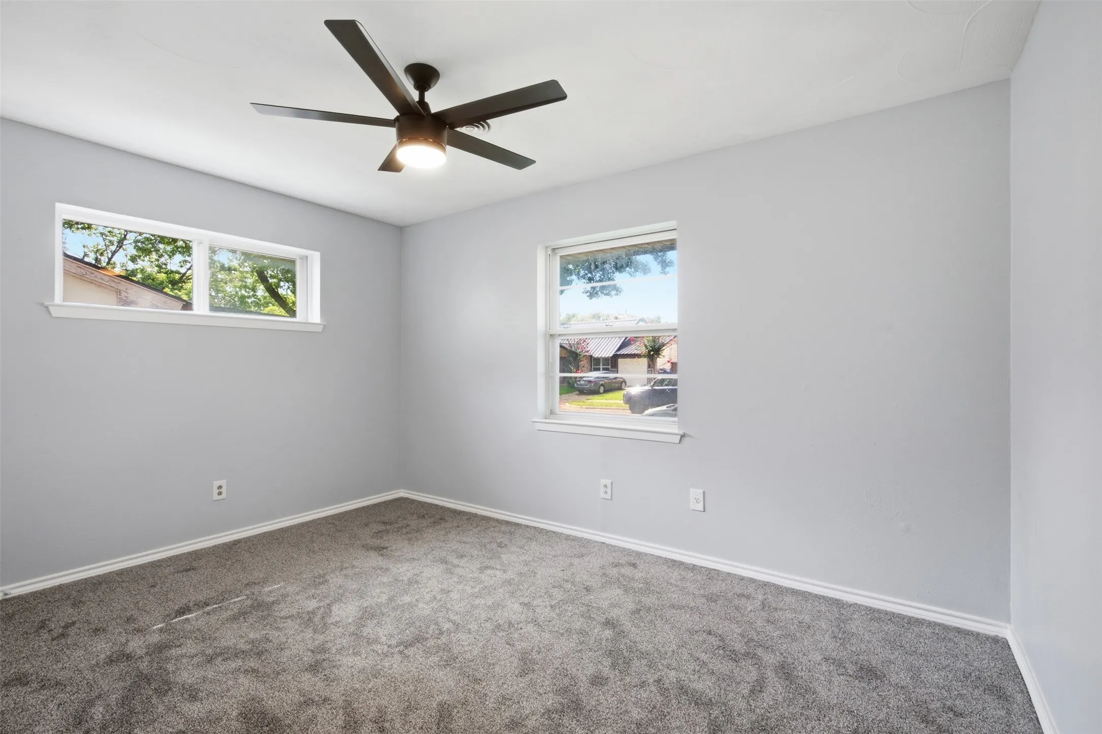Comfortable Main-Level Retreat — Fresh paint, new carpet, multiple windows, and a modern ceiling fan create a bright primary bedroom with plenty of flexibility for furniture placement.