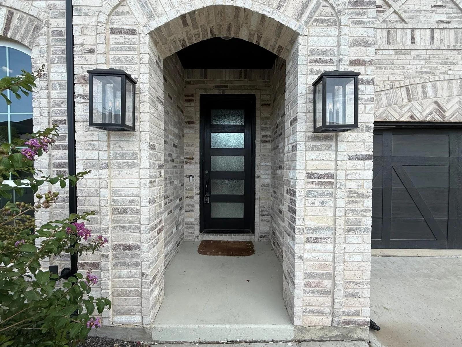 Arched entry featuring a modern black door with frosted glass panels