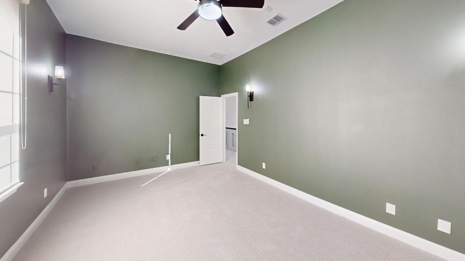Spacious room featuring carpet flooring, a ceiling fan, and wall sconces