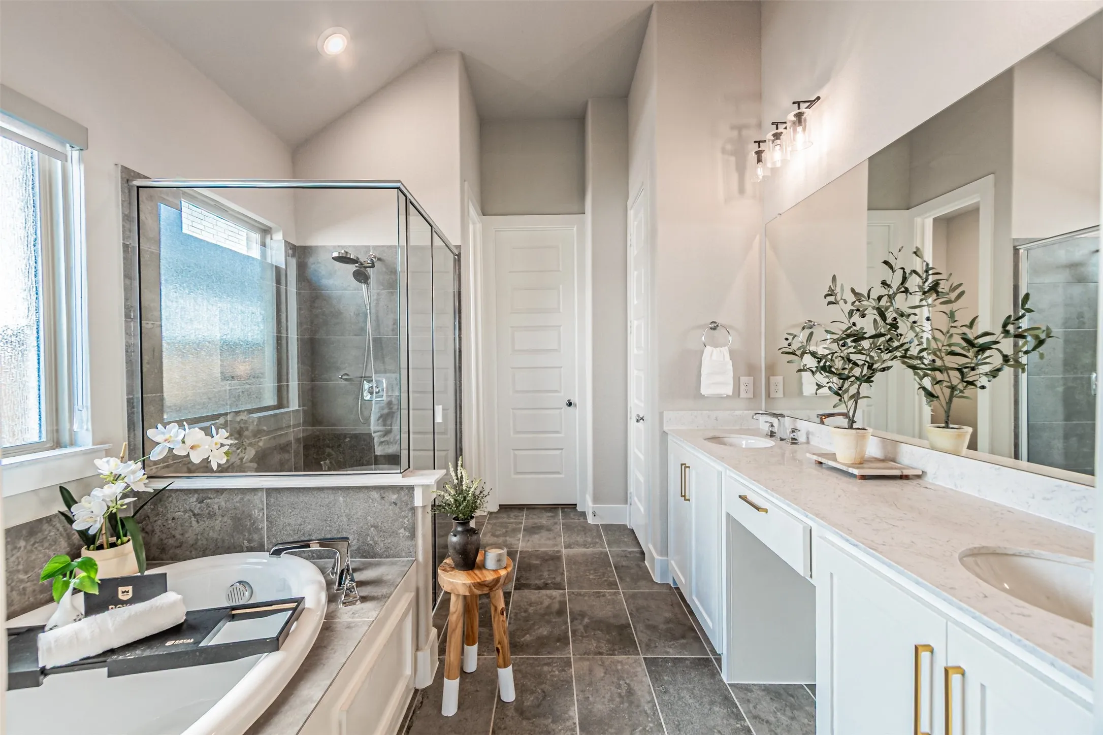 Bathroom featuring a built-in soaking tub, a walk-in shower with glass enclosure, and a double vanity with stone countertops