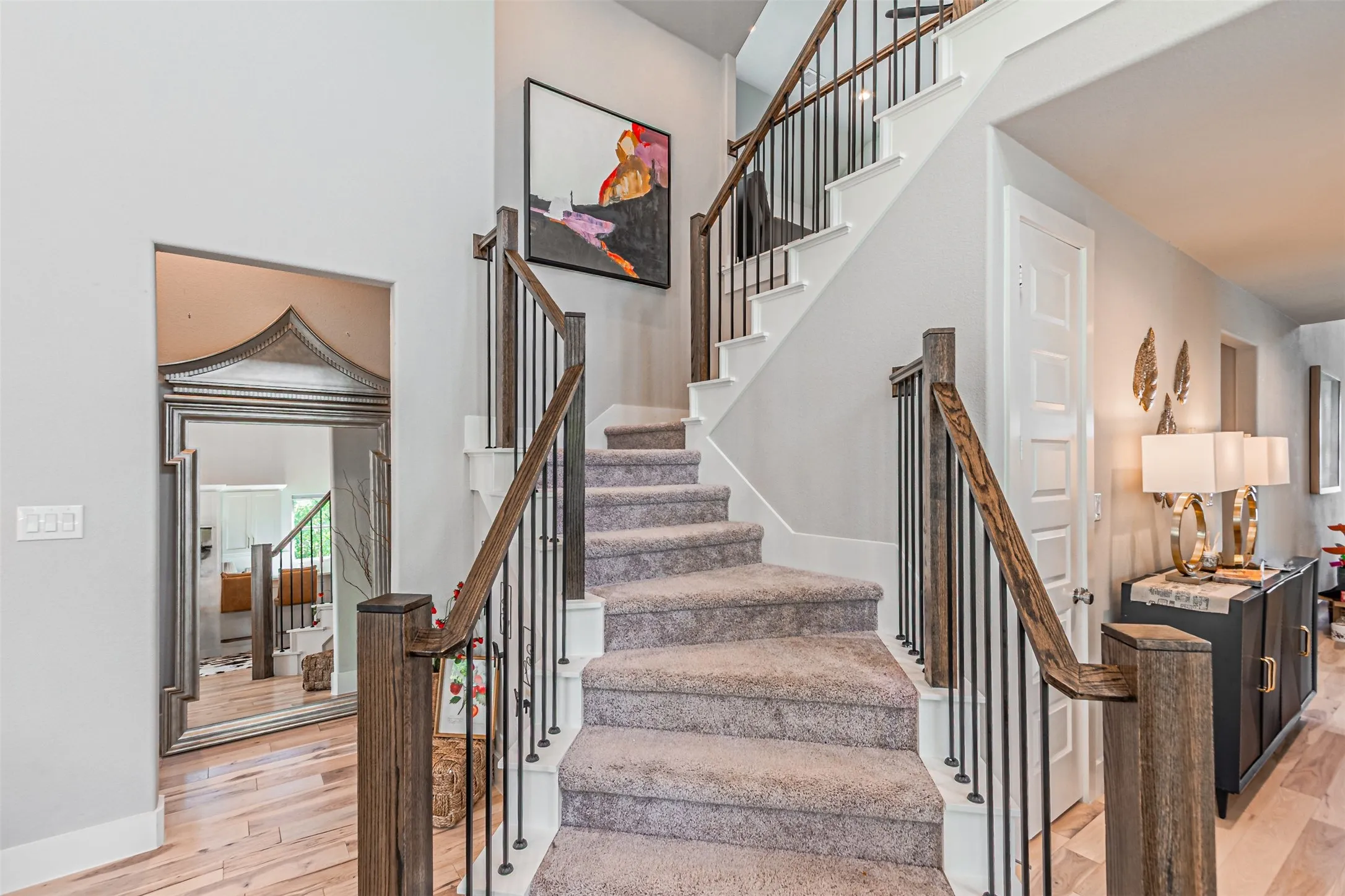 Carpeted staircase with dark wood newel posts and handrails, complemented by black iron balusters