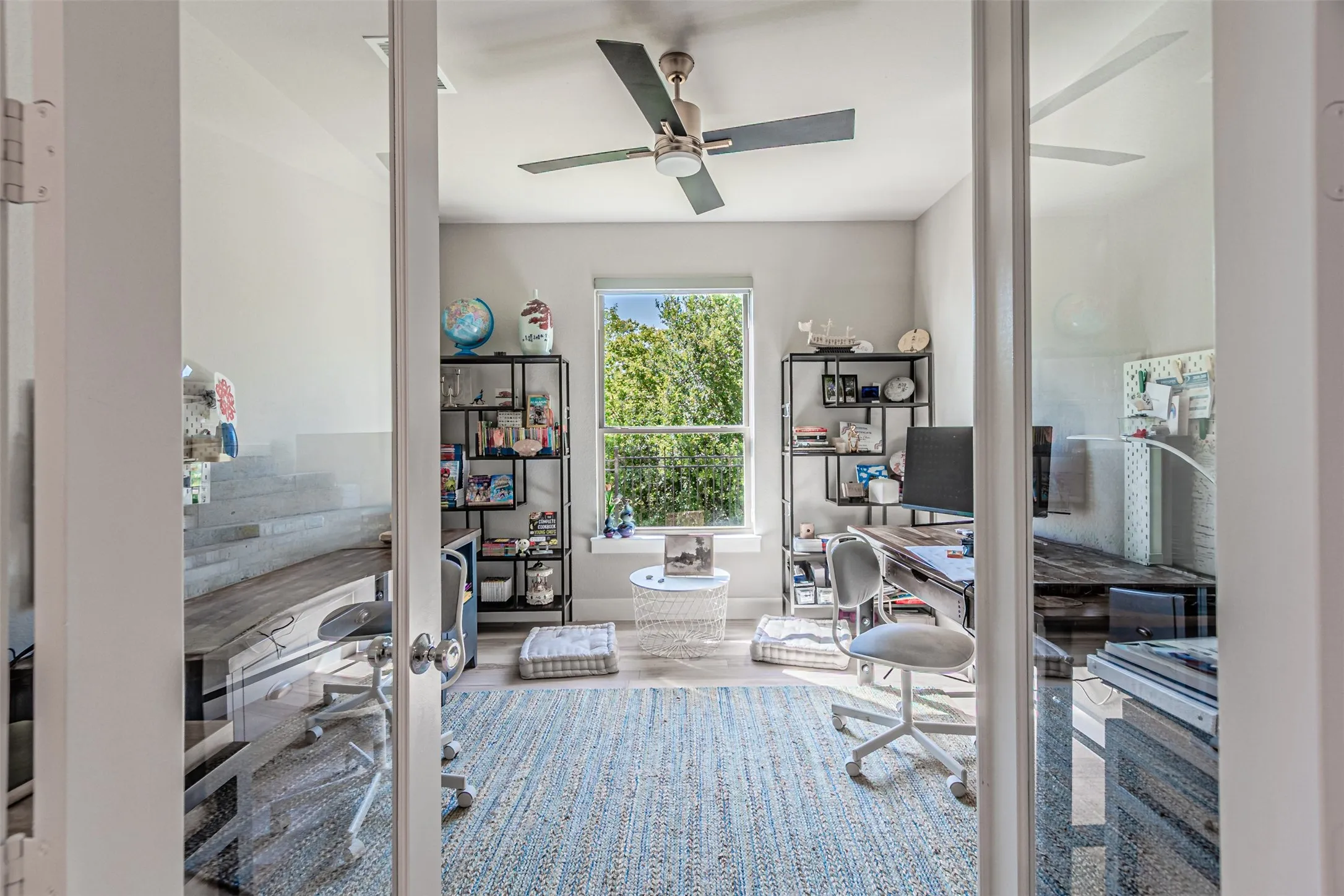 Room featuring a ceiling fan with integrated lighting, a large window offering natural light, and wood-finish flooring
