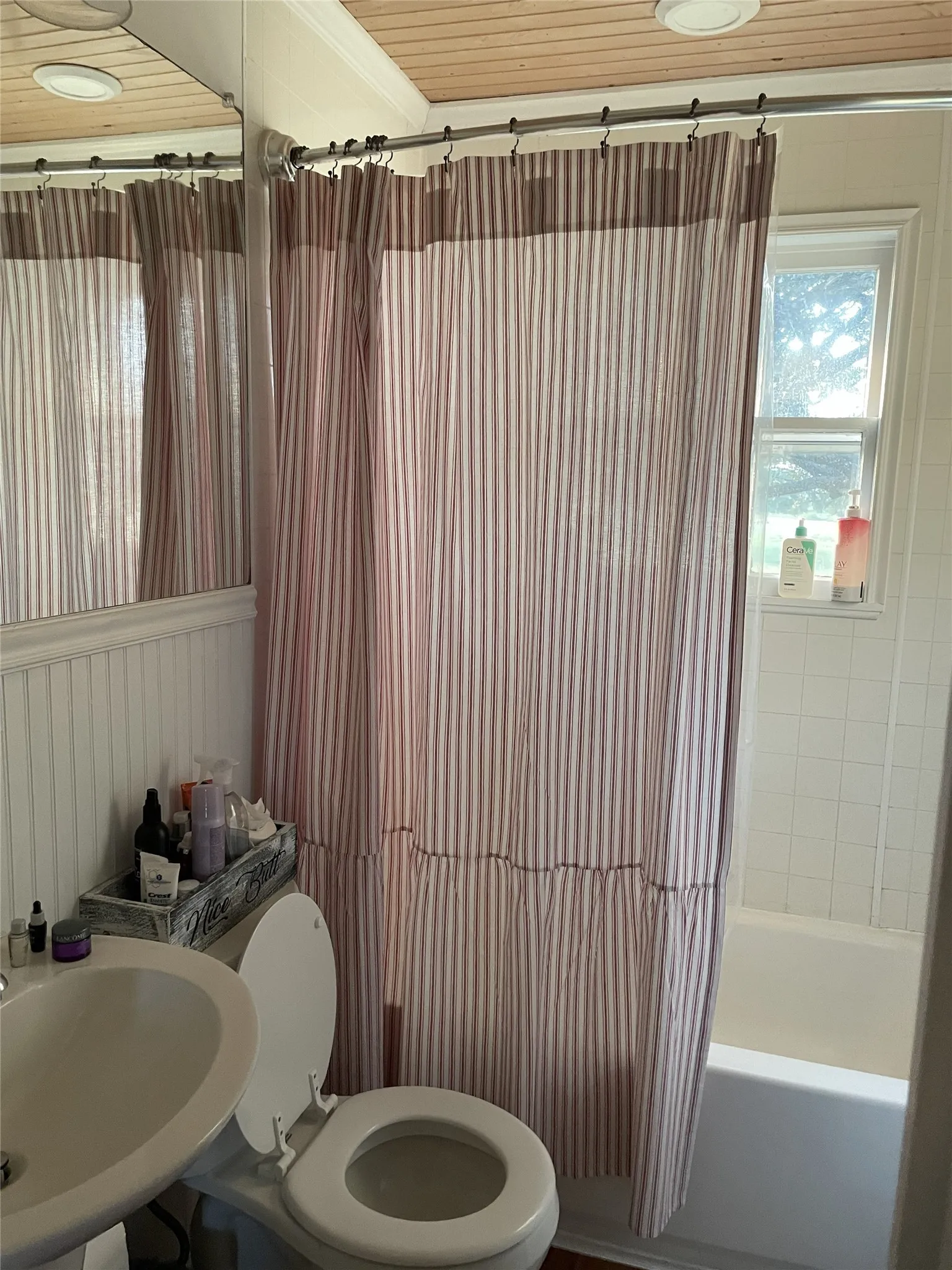 Bathroom featuring a white porcelain toilet, pedestal sink, beadboard wall paneling, and a wood-finish ceiling