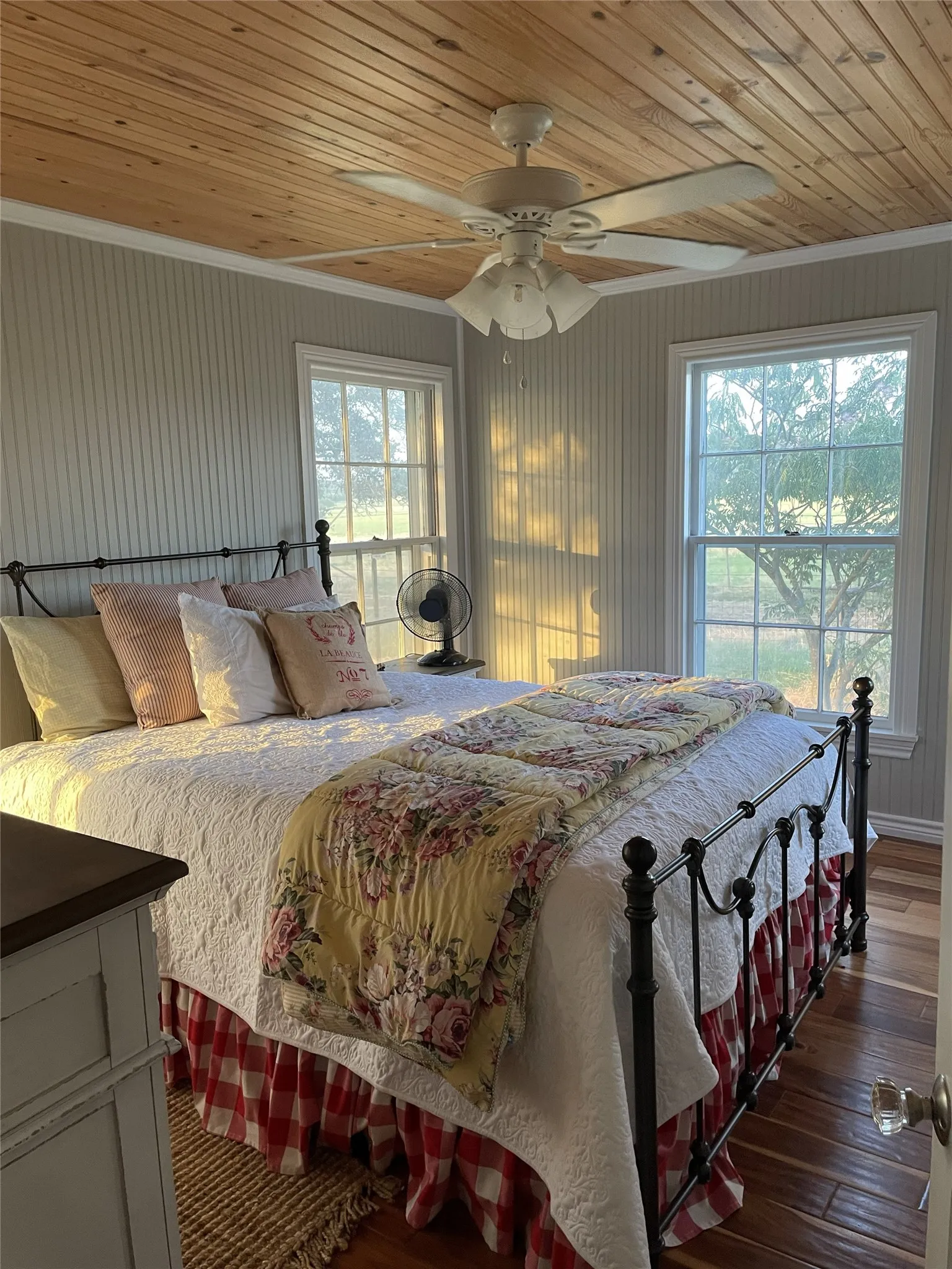 Wood-paneled ceiling with a central ceiling fan and light fixture