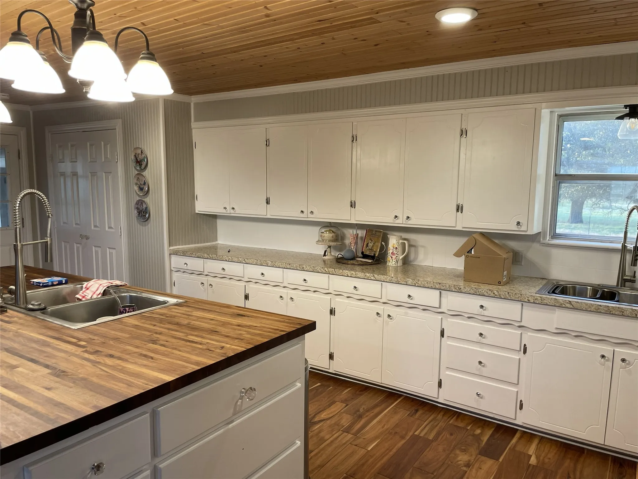 Kitchen featuring a wood-finish plank ceiling, wood-finish flooring, white cabinetry, and a butcher block island countertop with an undermount sink