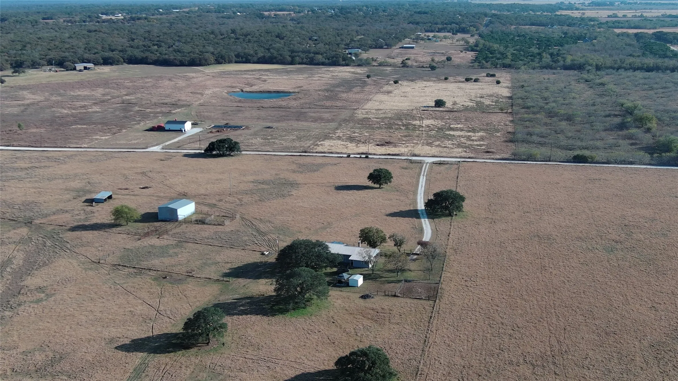 Expansive rural property featuring a main residence, multiple outbuildings, and a pond