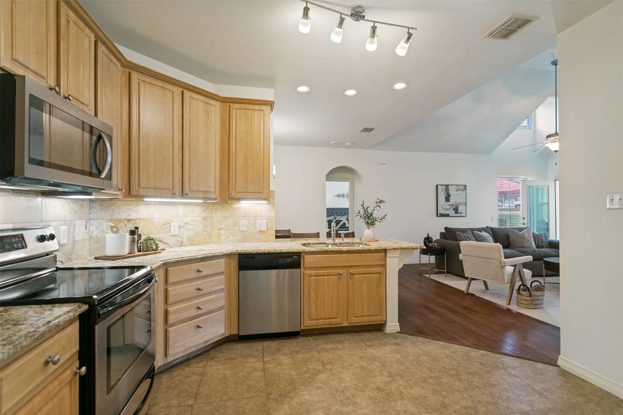 Another view of the kitchen, living, and dining. The archway leads to the primary bedroom and bath.
