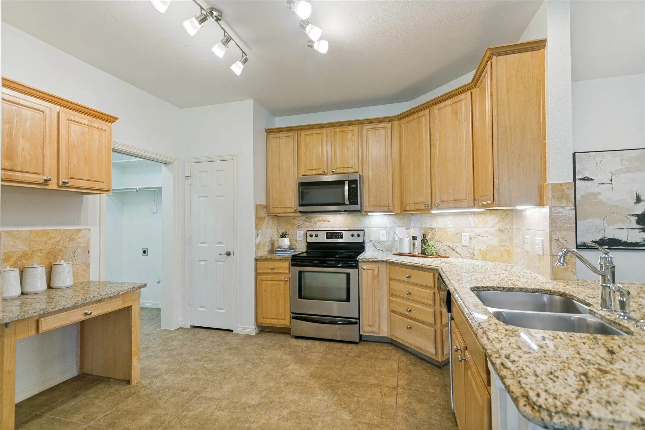 View of the kitchen leading into the utility room and a 2-car garage.  The kitchen also features a convenient command center for organization and meal planning.  The utility room provides additional storage with a second large pantry.