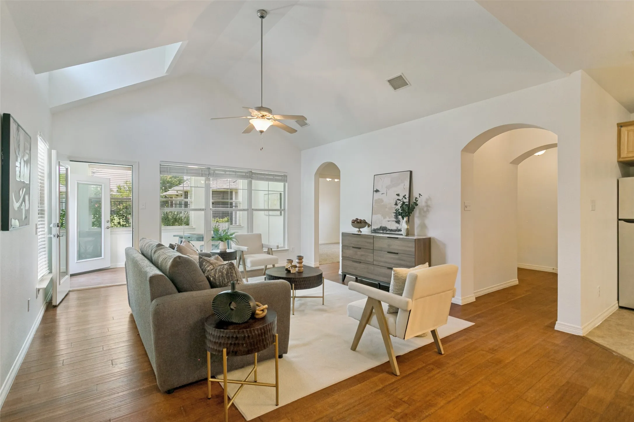 View from the living room highlighting the soaring ceilings, welcoming arched entryway, and bright, light-filled sunroom.