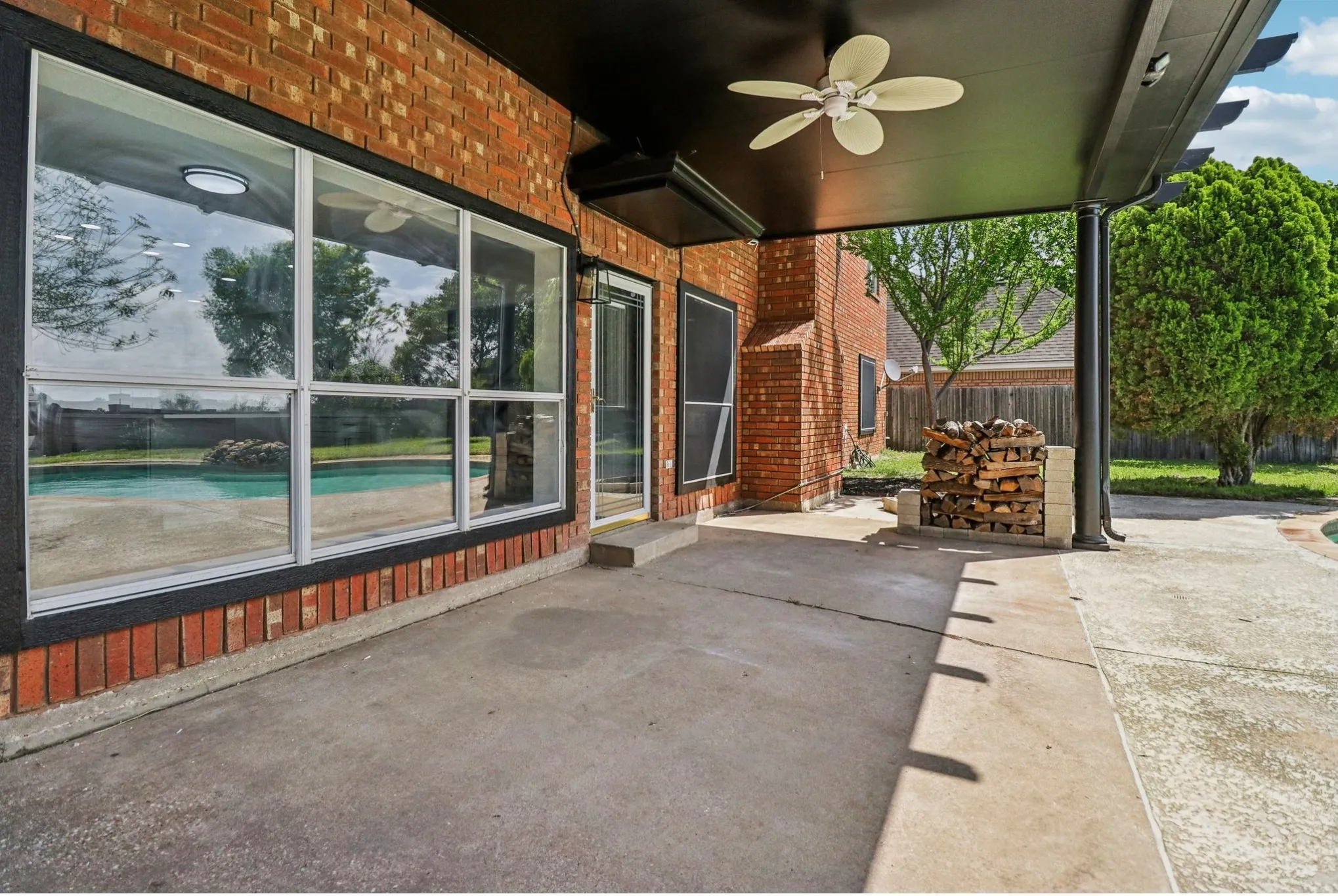 Covered patio overlooking the backyard and sparkling pool.