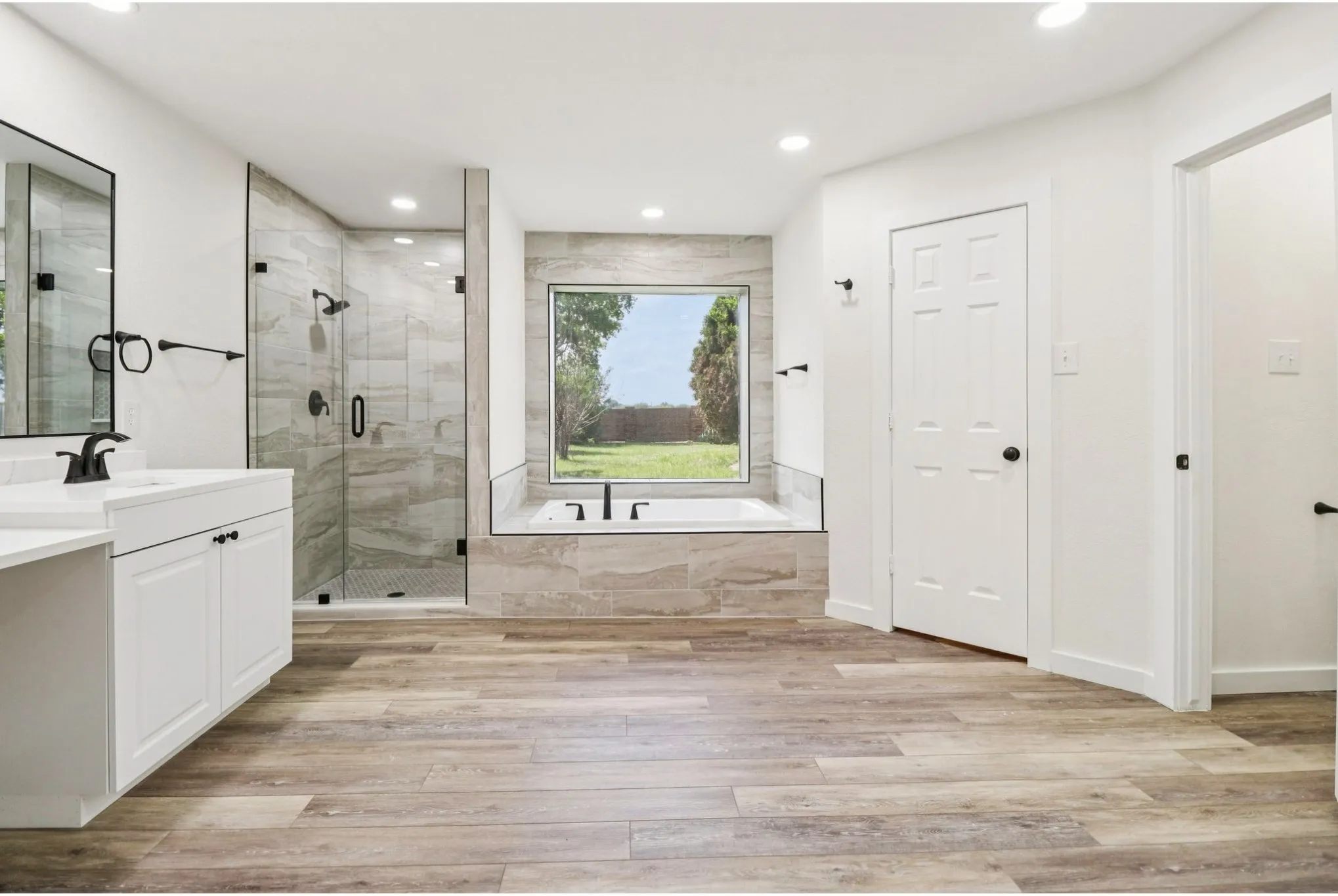 Spa-inspired primary bath with dual vanities, soaking tub, and separate shower.