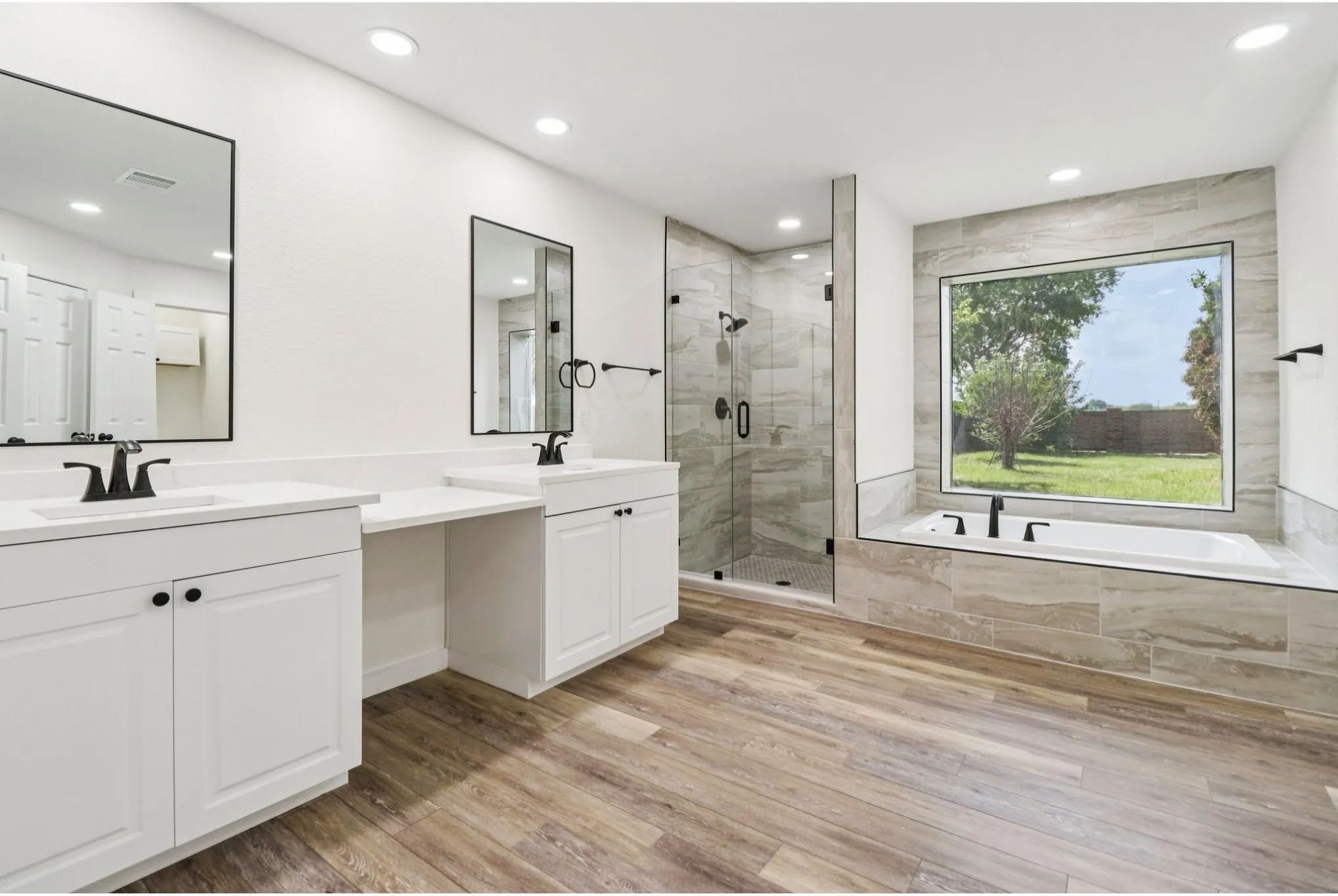 Spa-inspired primary bath with dual vanities, soaking tub, and separate shower.