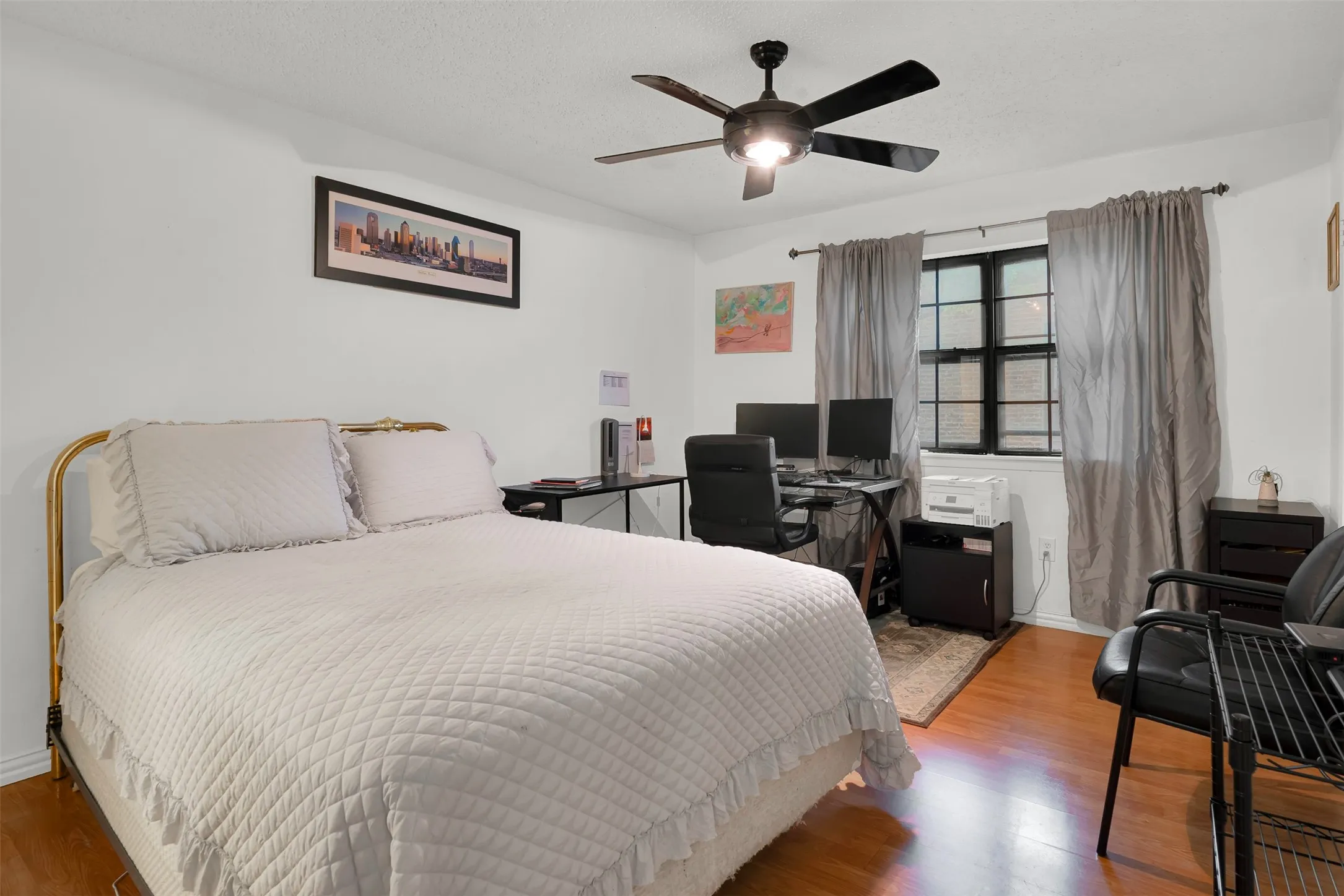 Spacious room featuring wood-finish flooring, a ceiling fan with integrated lighting, and a large window.