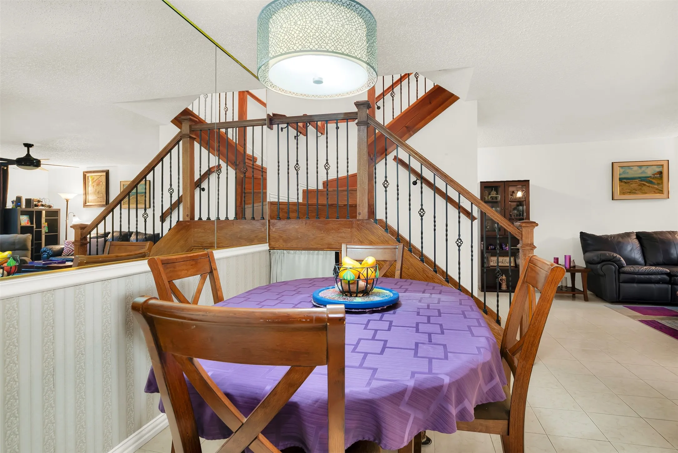 Dining area featuring a decorative chandelier with an open-concept design, wood-finish staircase with wrought iron balusters, and light-toned tile flooring