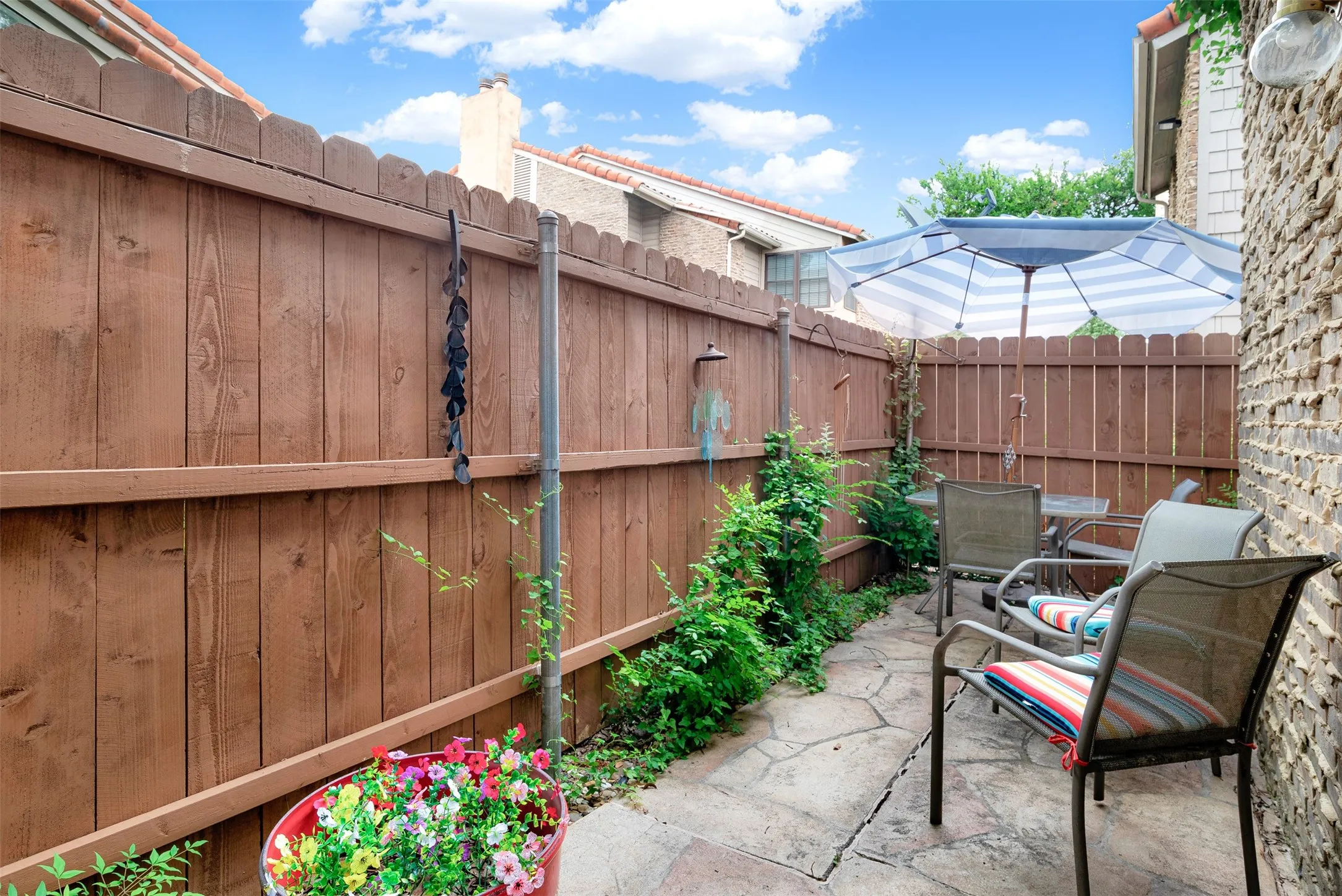 Private patio space featuring flagstone paving, a wood privacy fence, and landscaping.