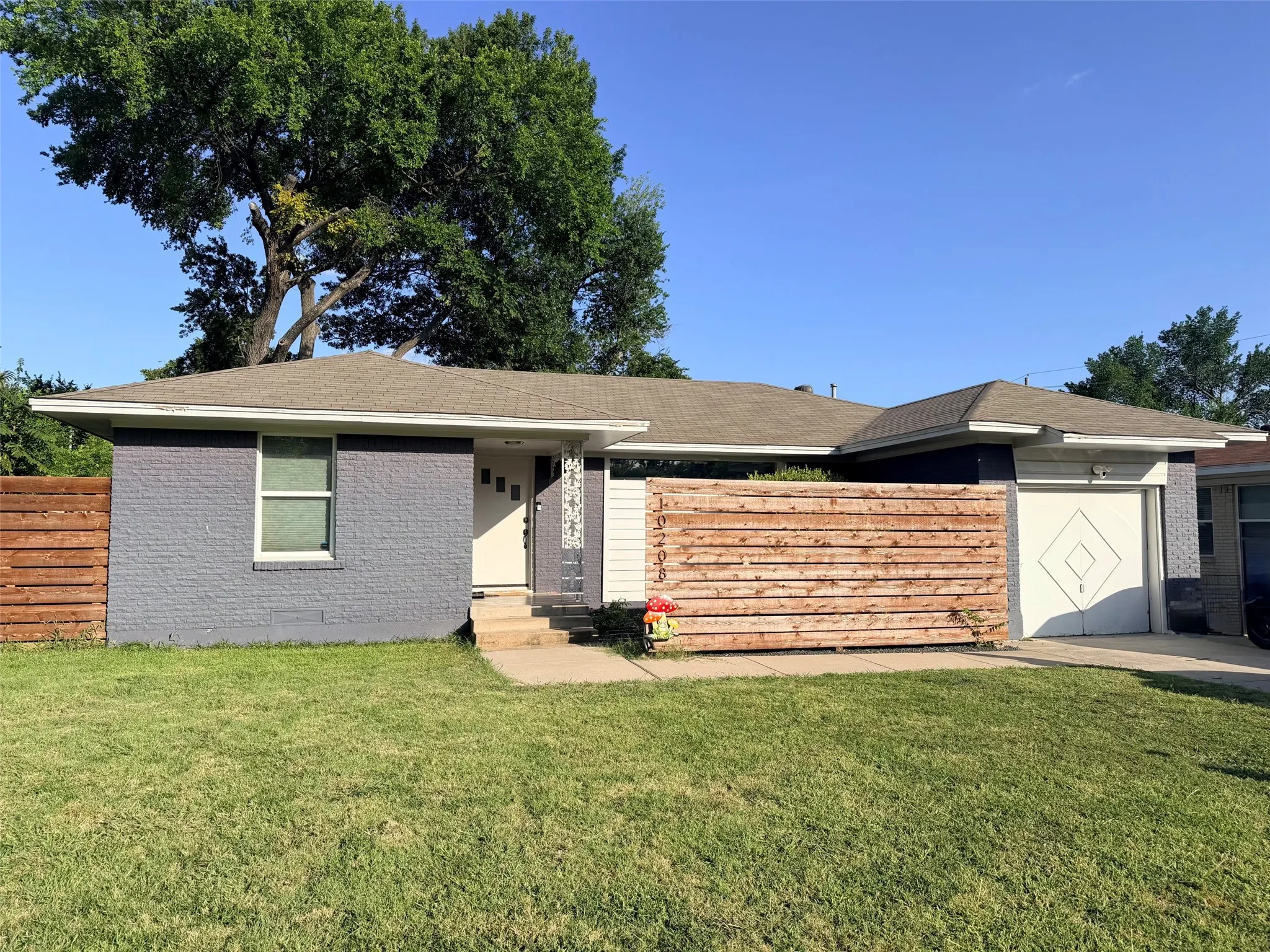 Adorable, Craftsman Style, Single-story residence featuring a gray brick facade and modern accent wood entry fence with address on fencing. So much potential here! Add some lush grren landscaping and make it your own!