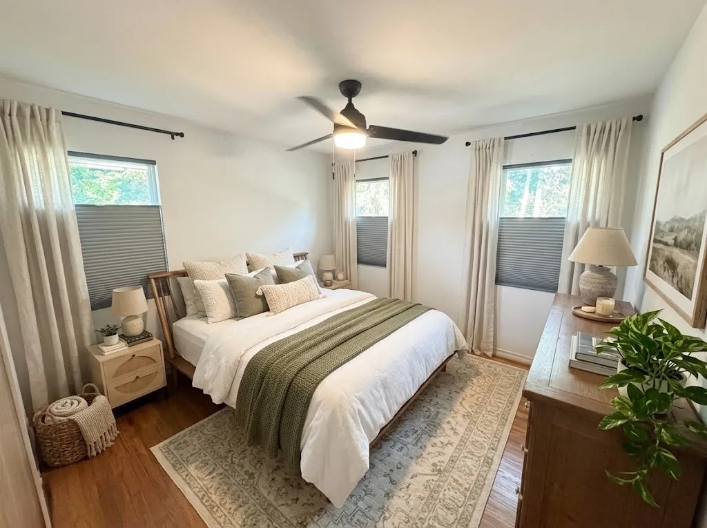 Hardwood flooring complemented by multiple windows, a ceiling fan with integrated lighting, and a neutral color palette
