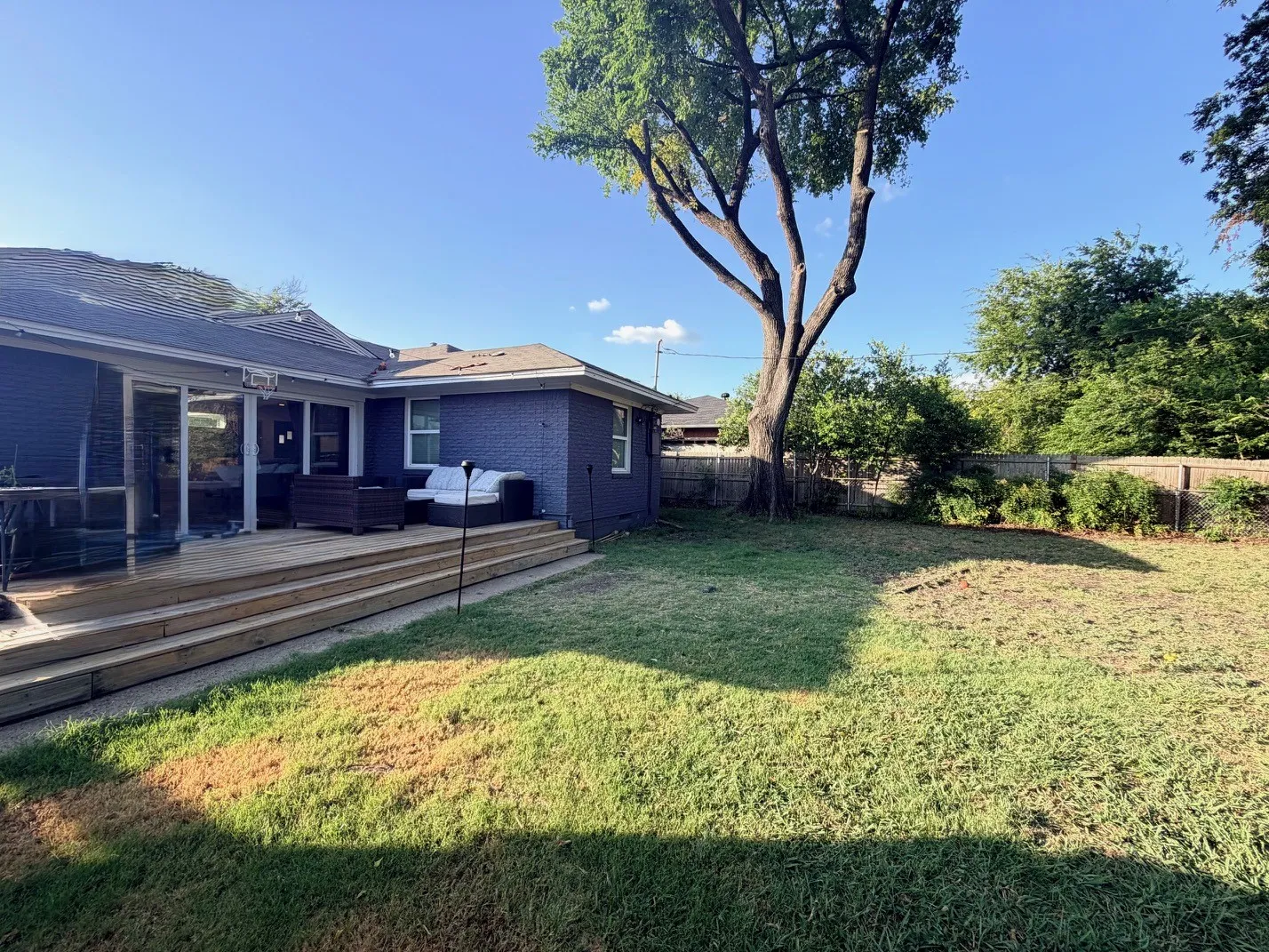 Expansive backyard featuring a multi-level wood deck, mature trees, and a wooden privacy fence