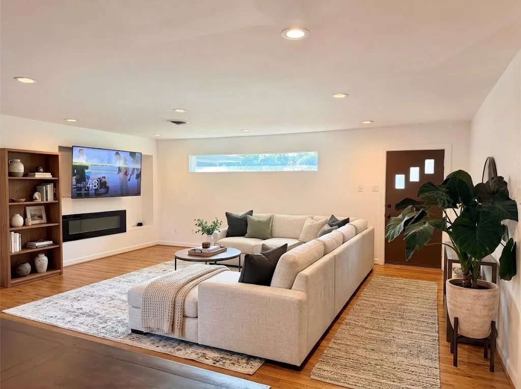 Main living area features wood-finish flooring, gorgeous built-in electric fireplace and a horizontal accent window. Open to the dining area and kitchen. Room has been virtually staged.