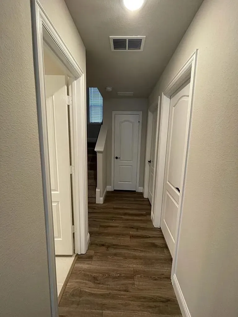 Hallway featuring wood-finish flooring, light neutral wall tones, white trim, and a flush-mount ceiling light