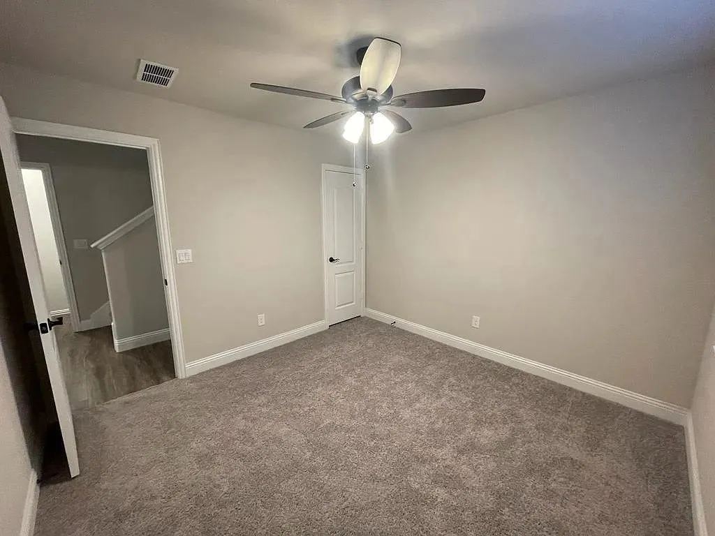 Carpeted room with neutral wall tones and a ceiling fan with integrated lighting