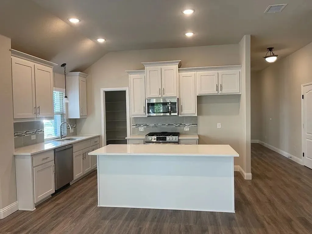 Modern kitchen featuring light cabinetry, stainless steel appliances, a center island with countertop seating, and wood-finish flooring