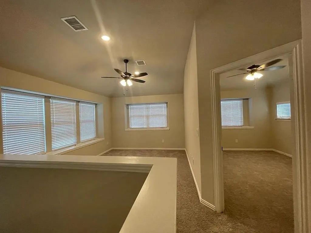 Versatile bonus room featuring multiple windows with blinds, recessed lighting, and a ceiling fan