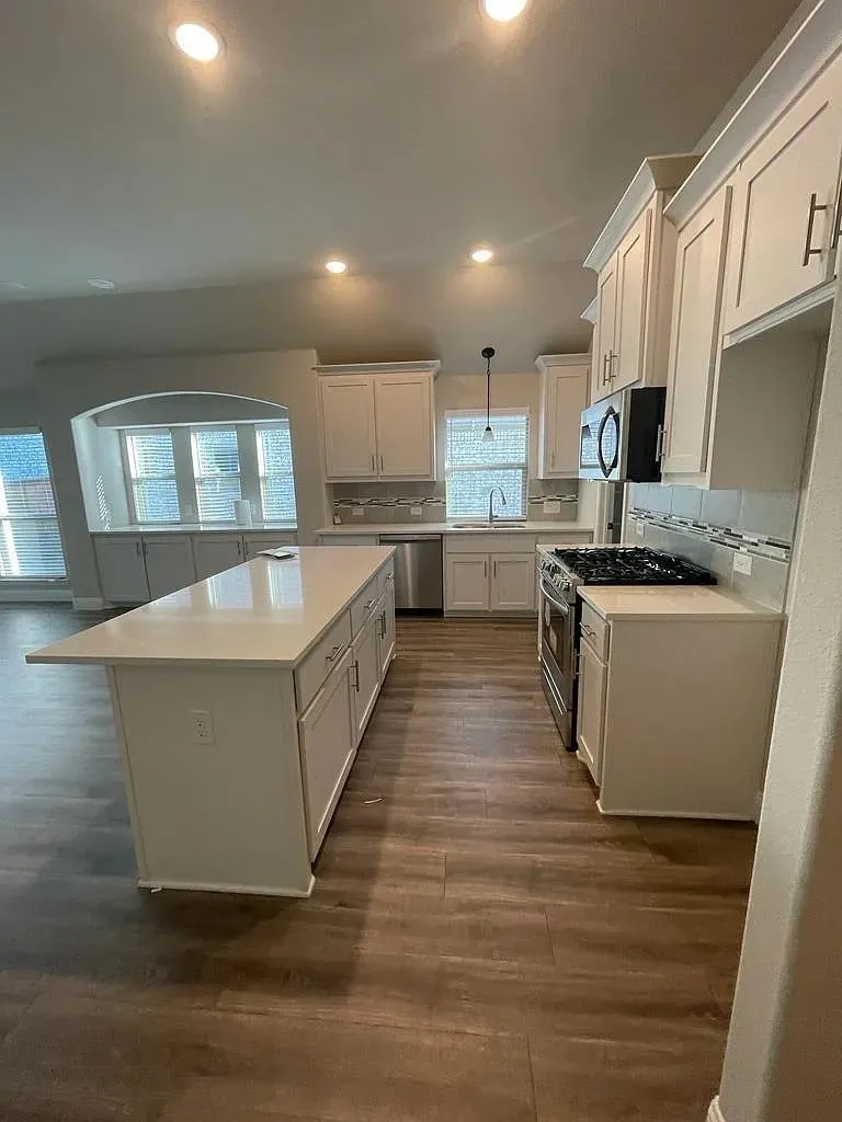 Open-concept kitchen featuring an expansive central island with a solid surface countertop and ample cabinetry