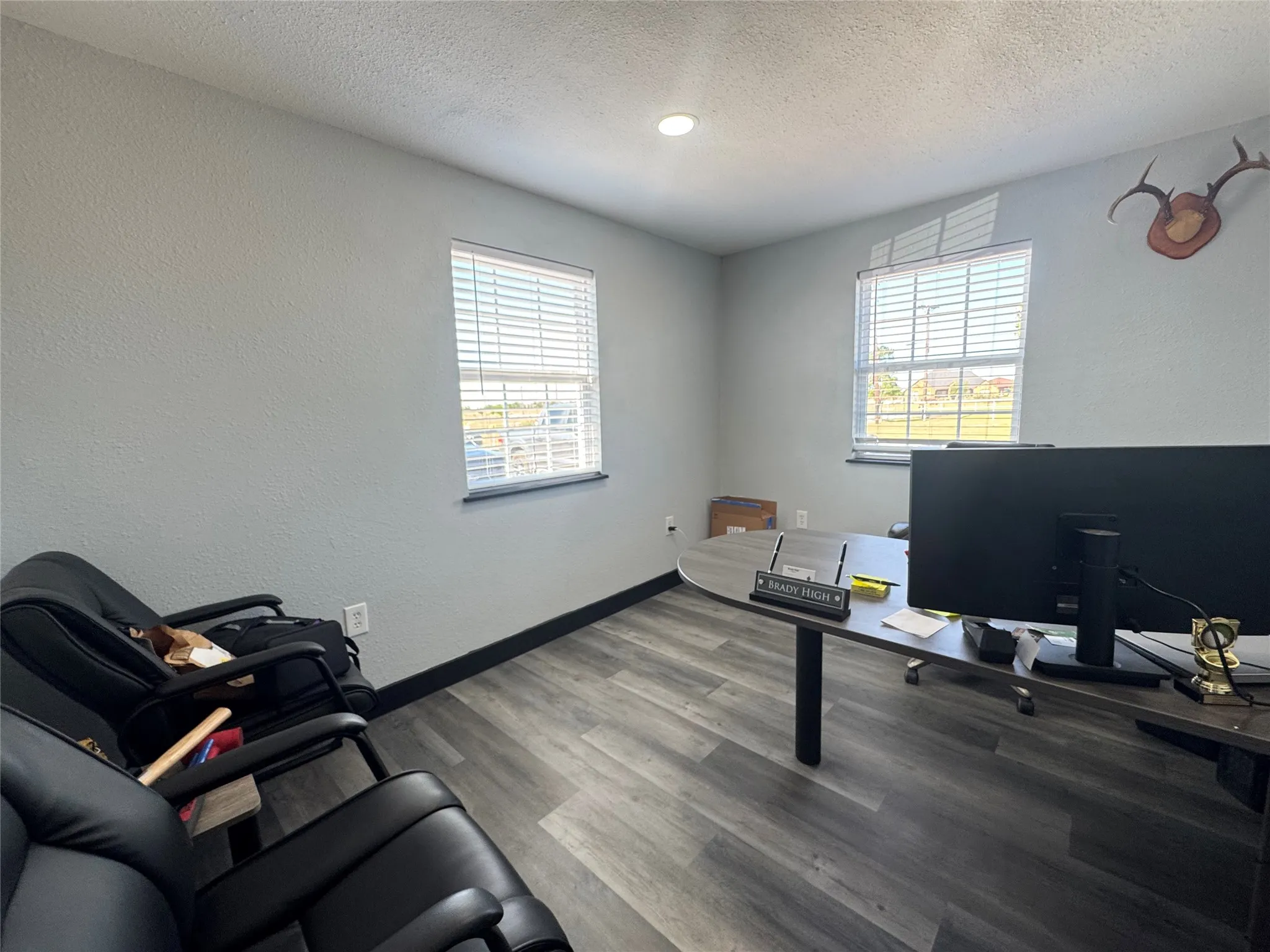 Room featuring wood-finish flooring, two windows with blinds, light gray walls, and recessed lighting