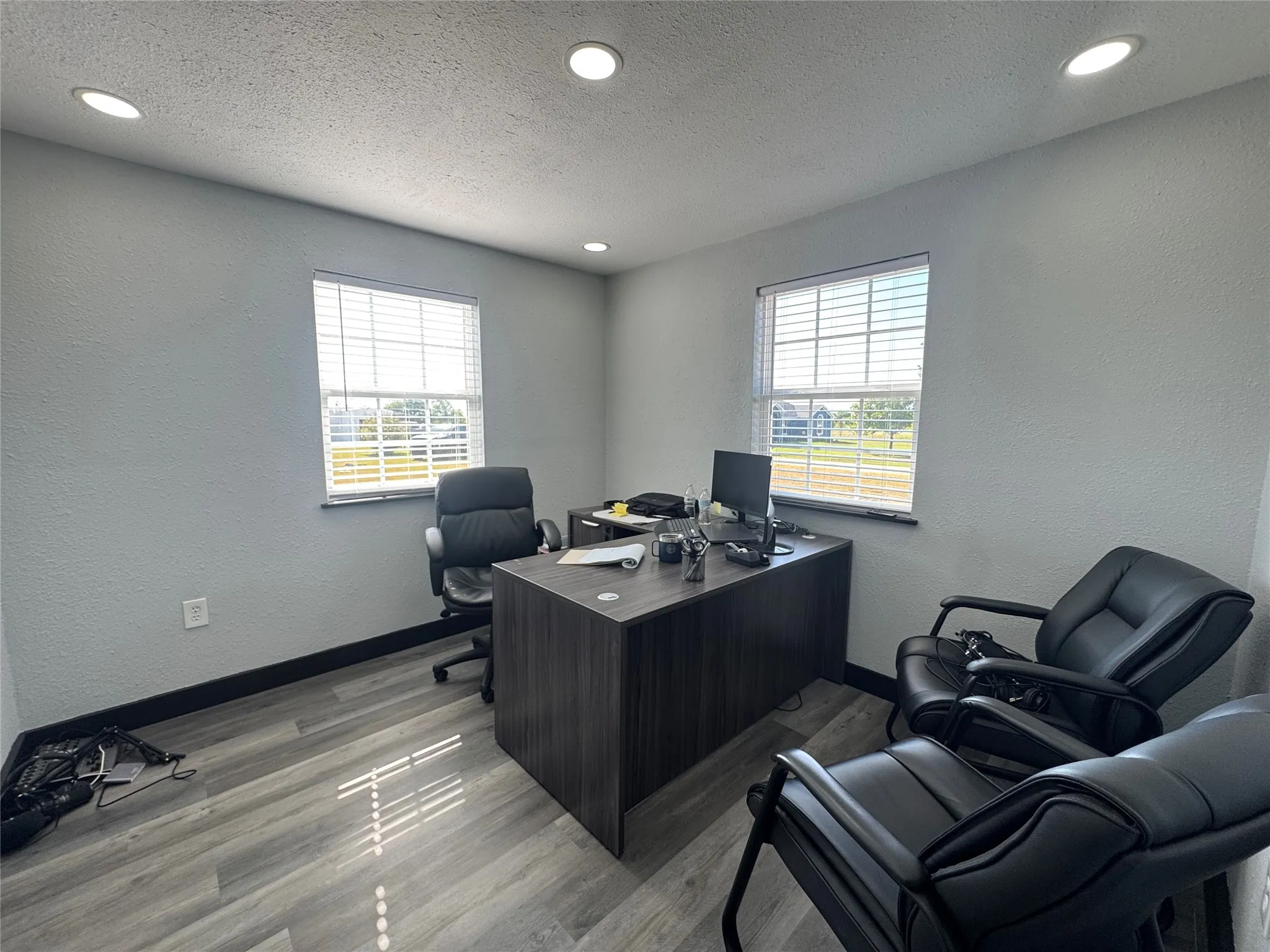 Office space featuring wood-finish flooring, two windows with blinds, recessed lighting, and a modern desk