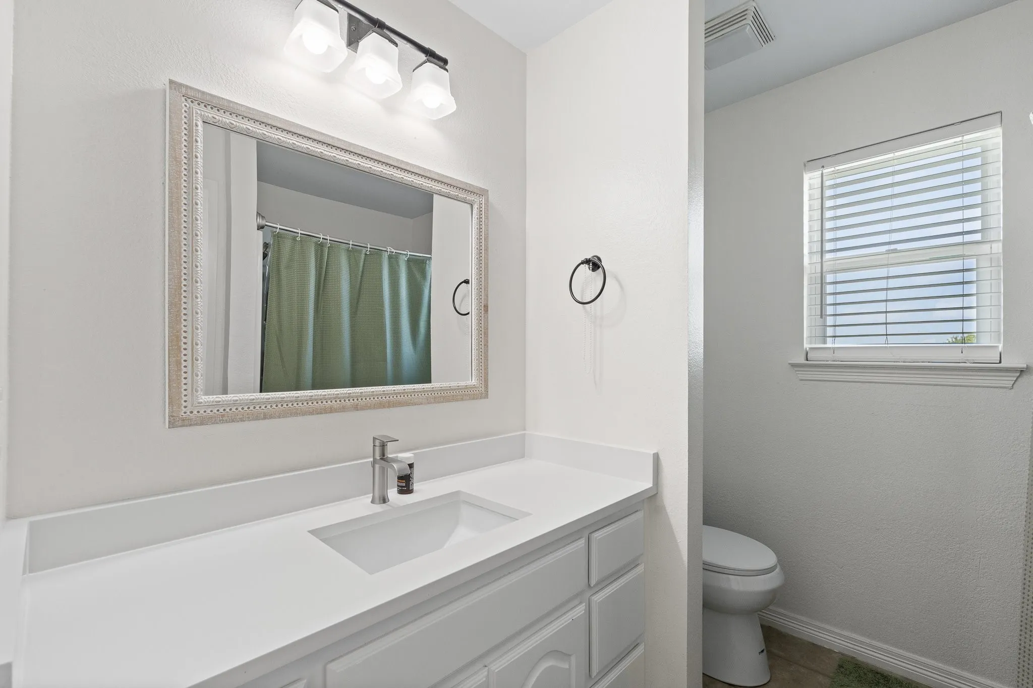 Vanity with a rectangular undermount sink, a chrome single-handle faucet, and a white countertop