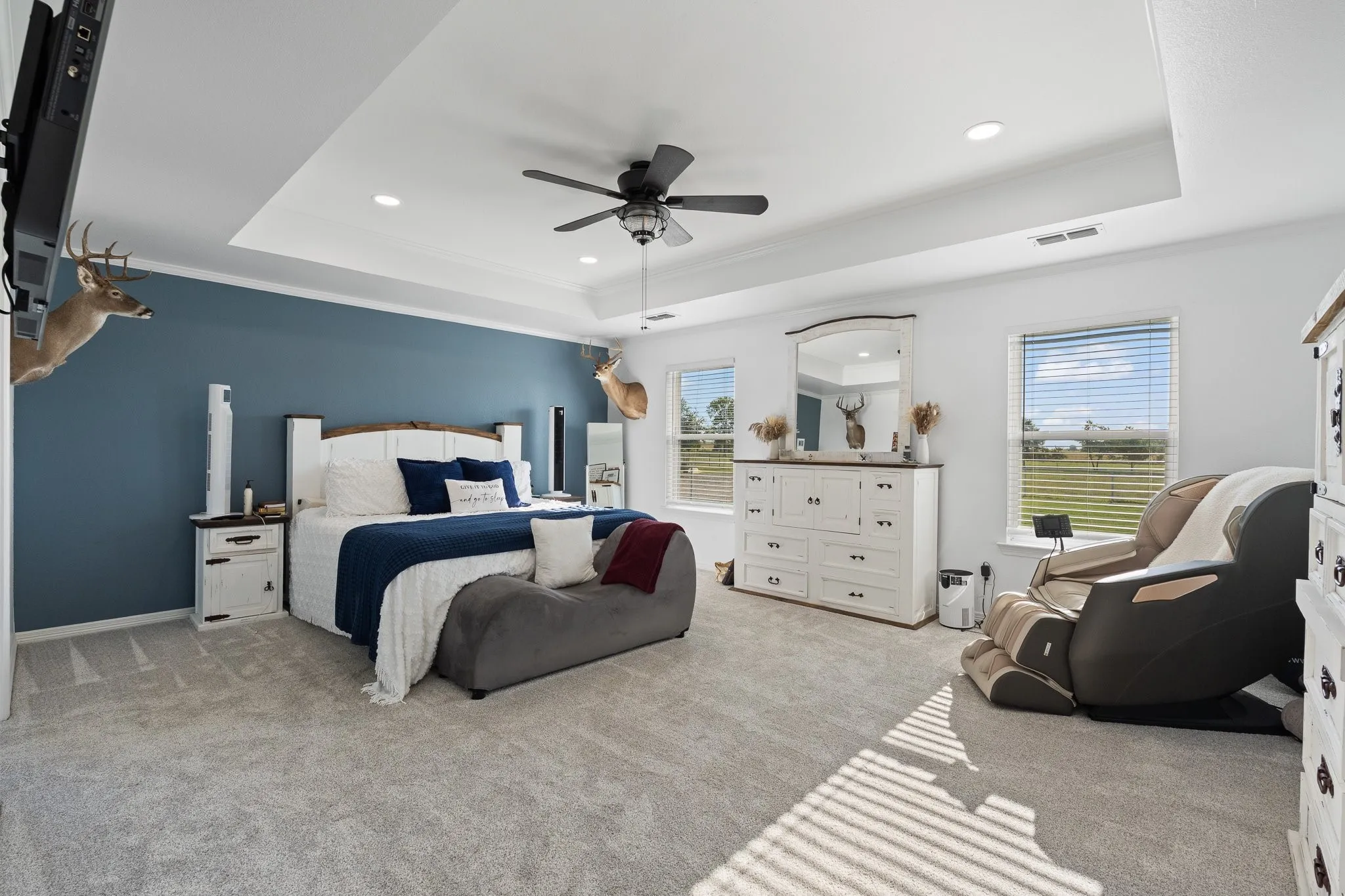 Spacious room featuring a tray ceiling with recessed lighting, ceiling fan, and carpeted flooring