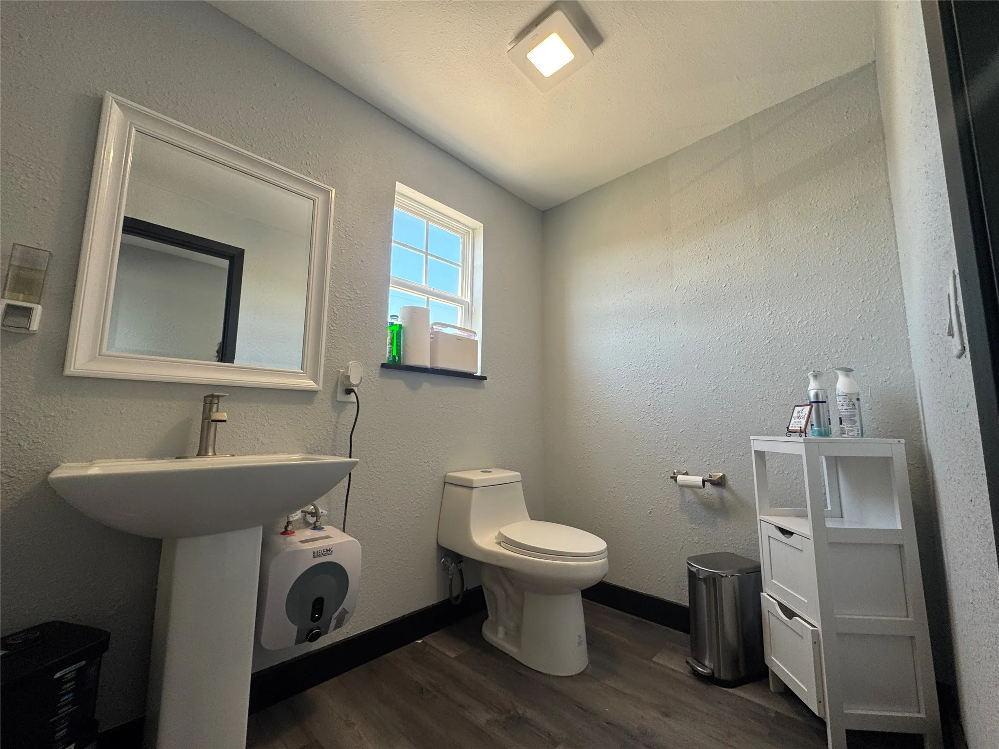 Pedestal sink with a brushed nickel faucet and a framed mirror