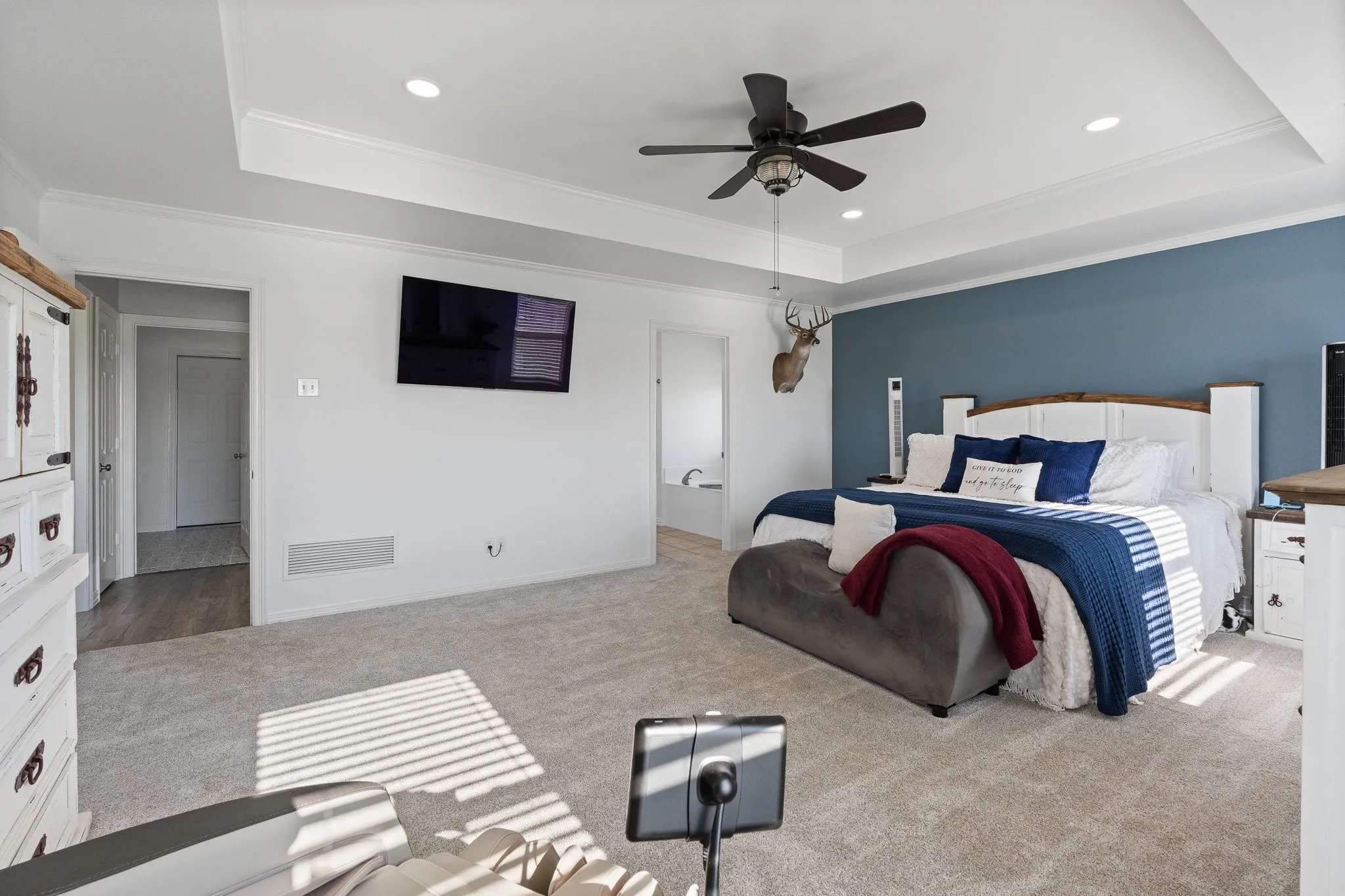 Spacious room featuring tray ceilings with recessed lighting, crown molding, and a ceiling fan