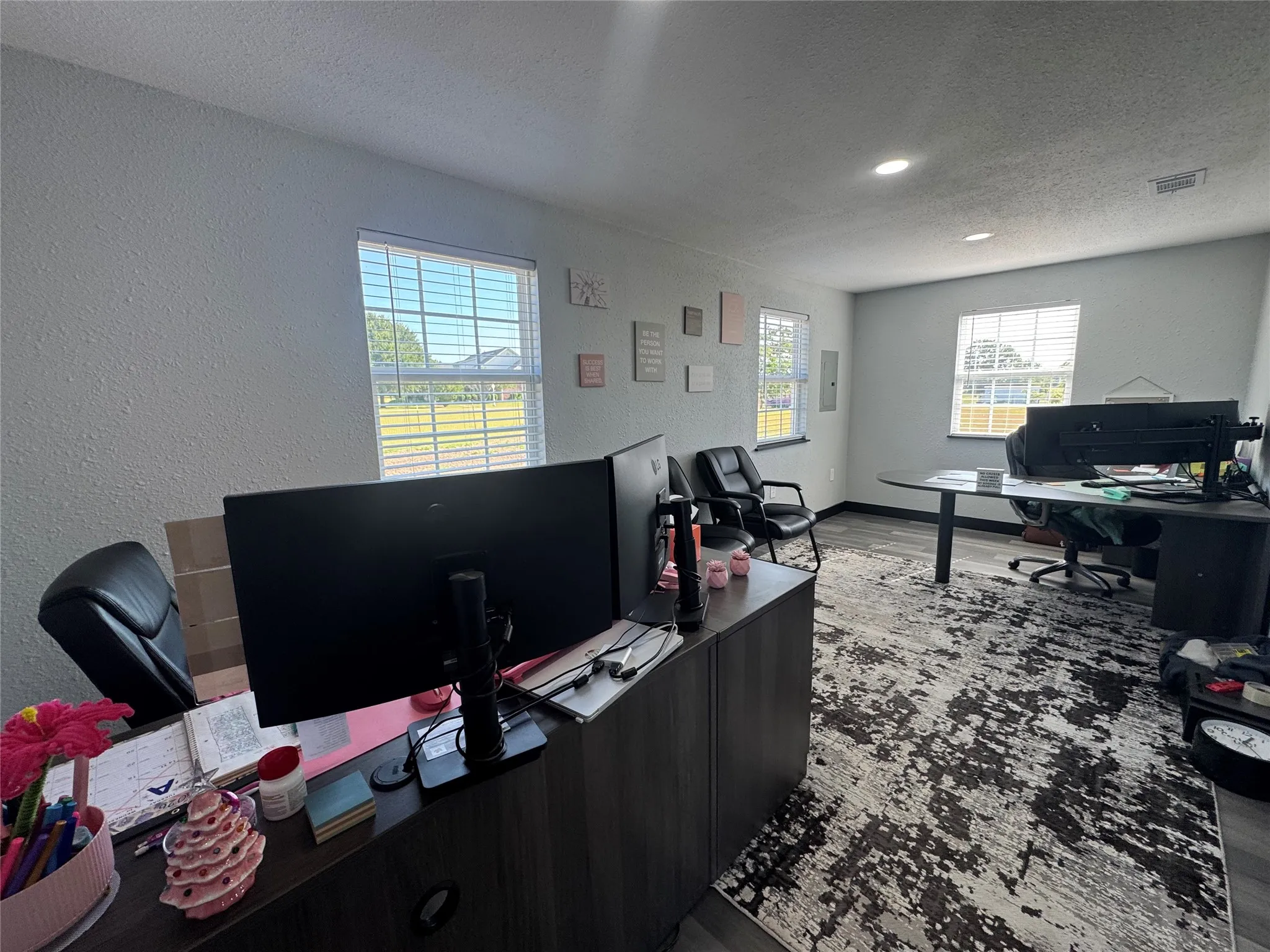 Spacious room featuring multiple windows with blinds, recessed lighting, and wood-finish flooring