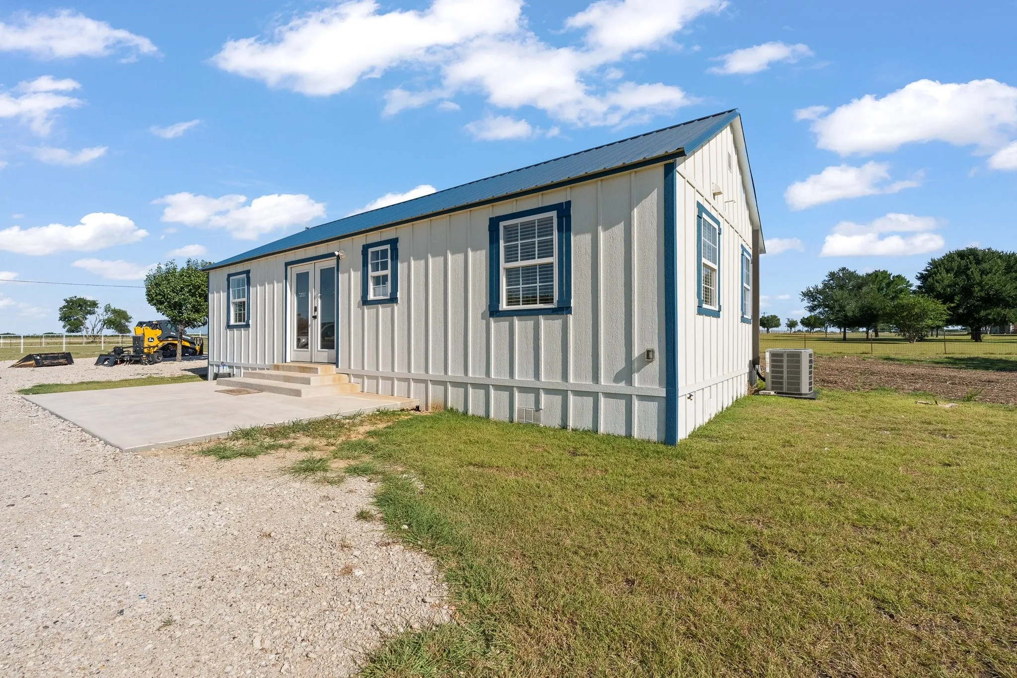 White vertical siding exterior with blue trim and a blue metal roof